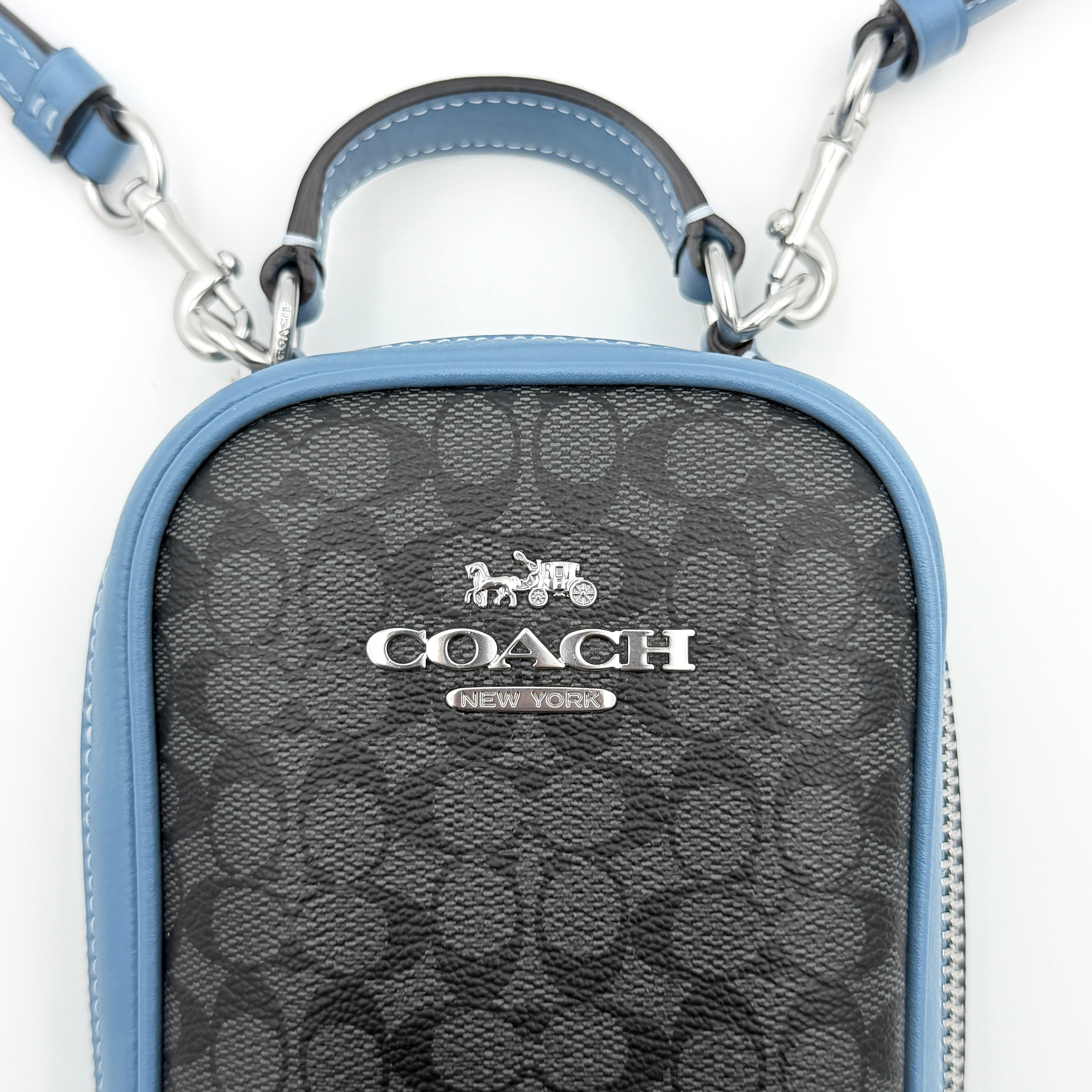 Coach Signature Eva Phone Crossbody in black coated canvas with blue leather trim and silver hardware displayed with its crossbody strap.