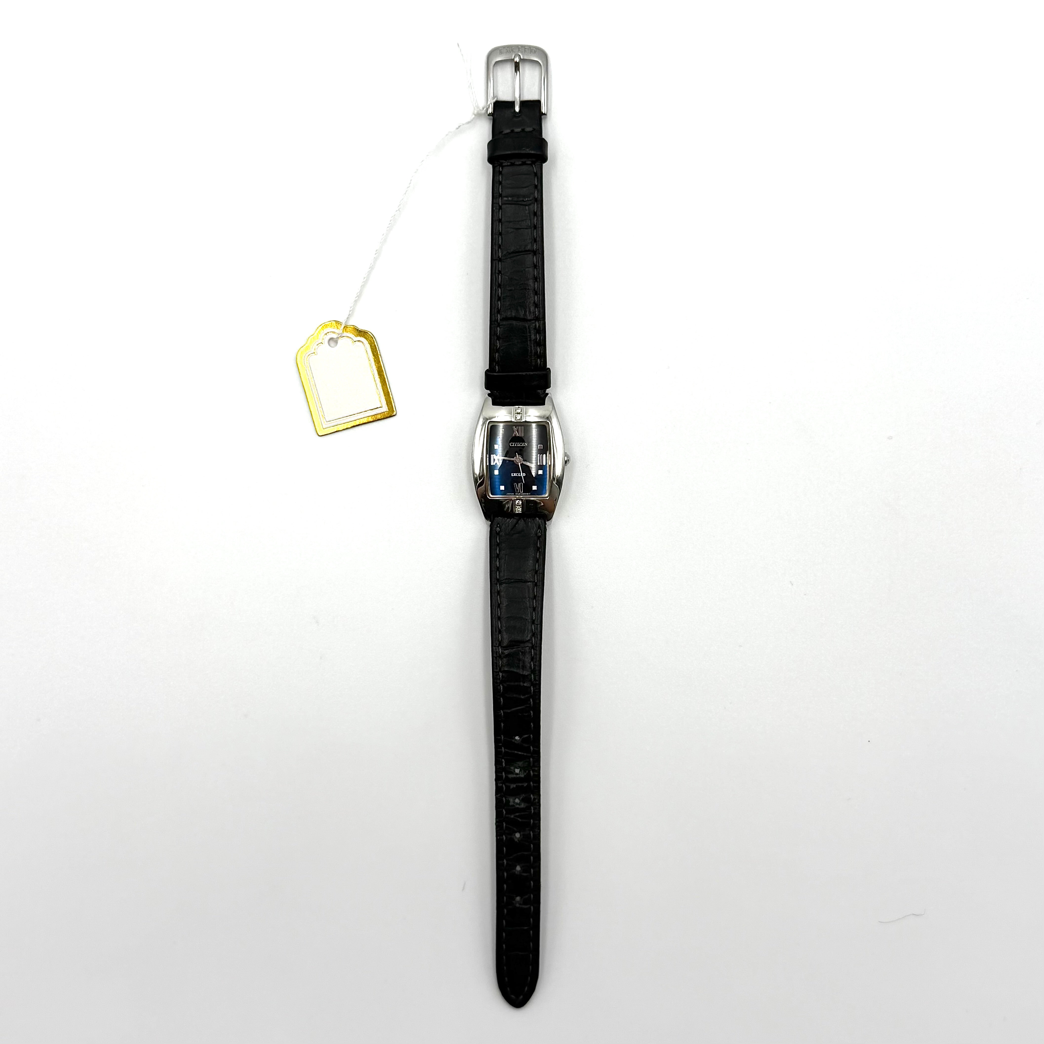Citizen Exceed watch featuring a dark blue dial, tonneau-shaped stainless steel case, and black leather strap displayed on a black cushion.