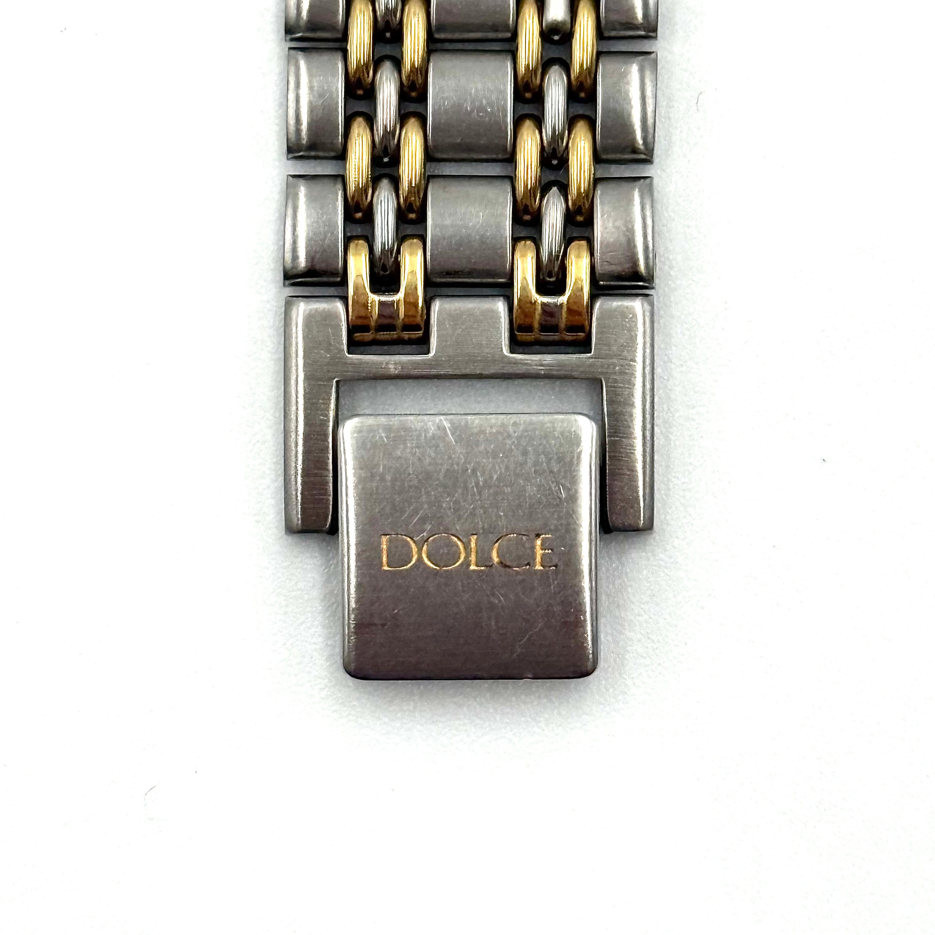 Seiko Dolce 5E31-6B90 watch in stainless steel with gold-tone accents and a cream dial, displayed on a black cushion.