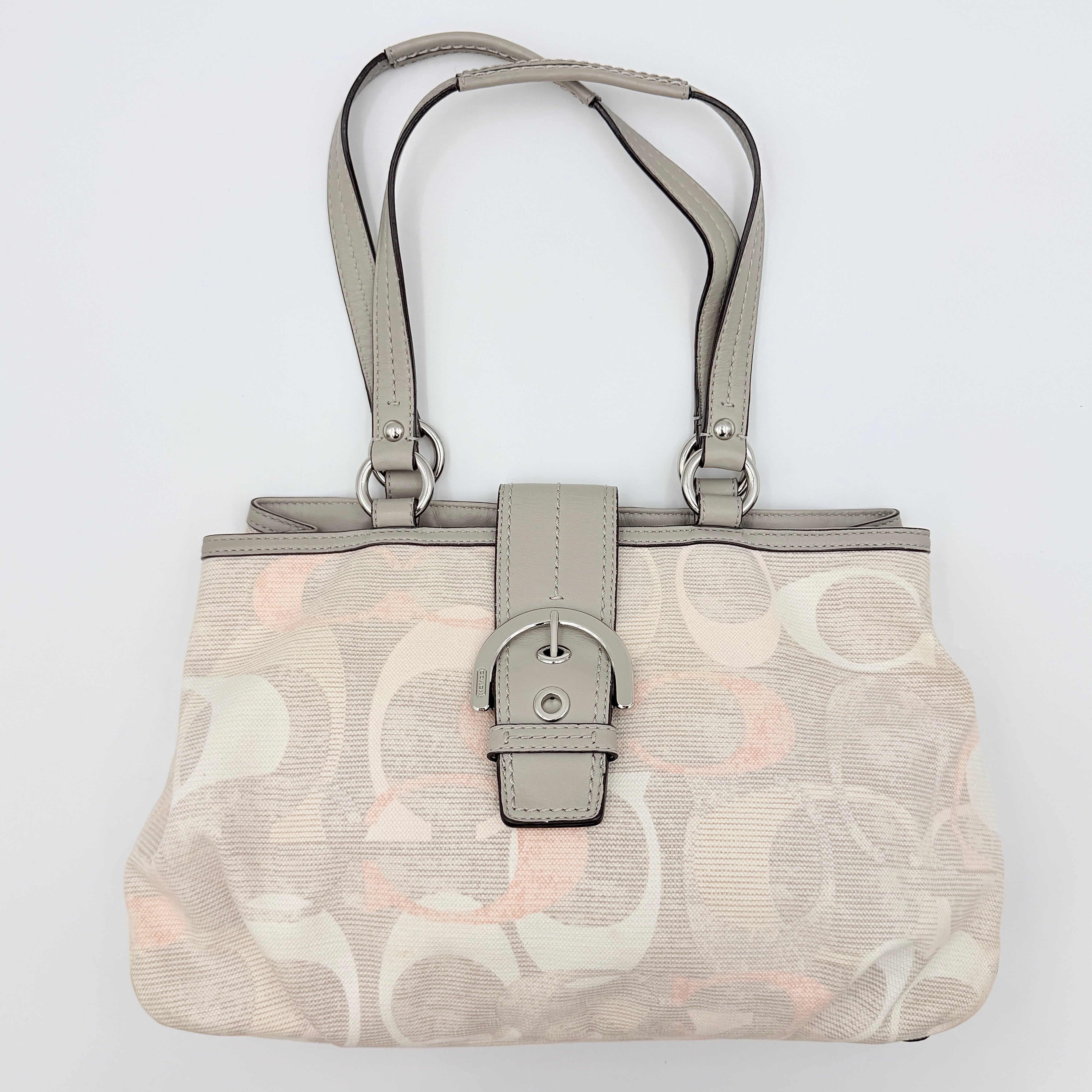 Coach Signature Optic Soho Shoulder Bag in grey and pink canvas with leather handles and buckle detail, shown against a white background.