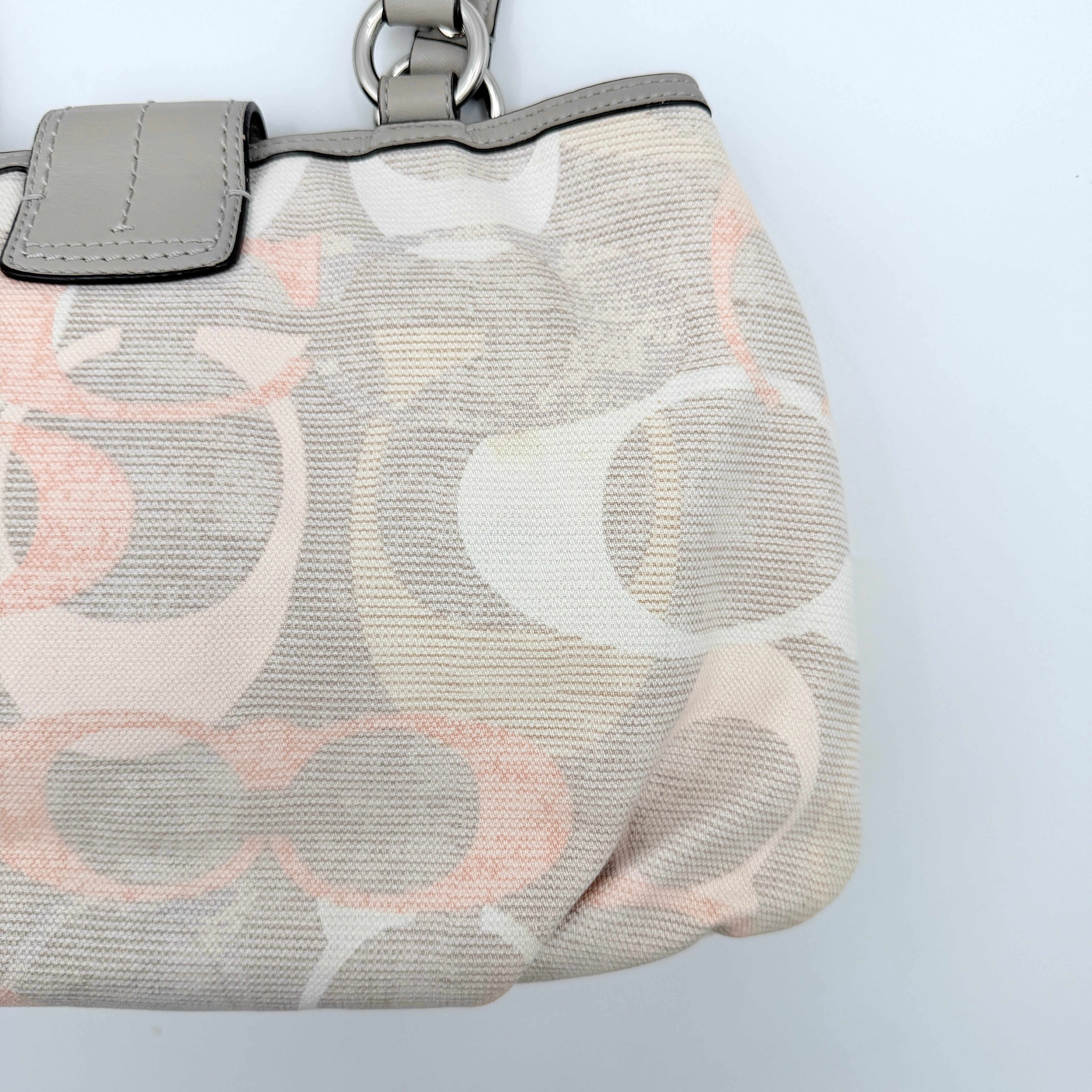 Coach Signature Optic Soho Shoulder Bag in grey and pink canvas with leather handles and buckle detail, shown against a white background.