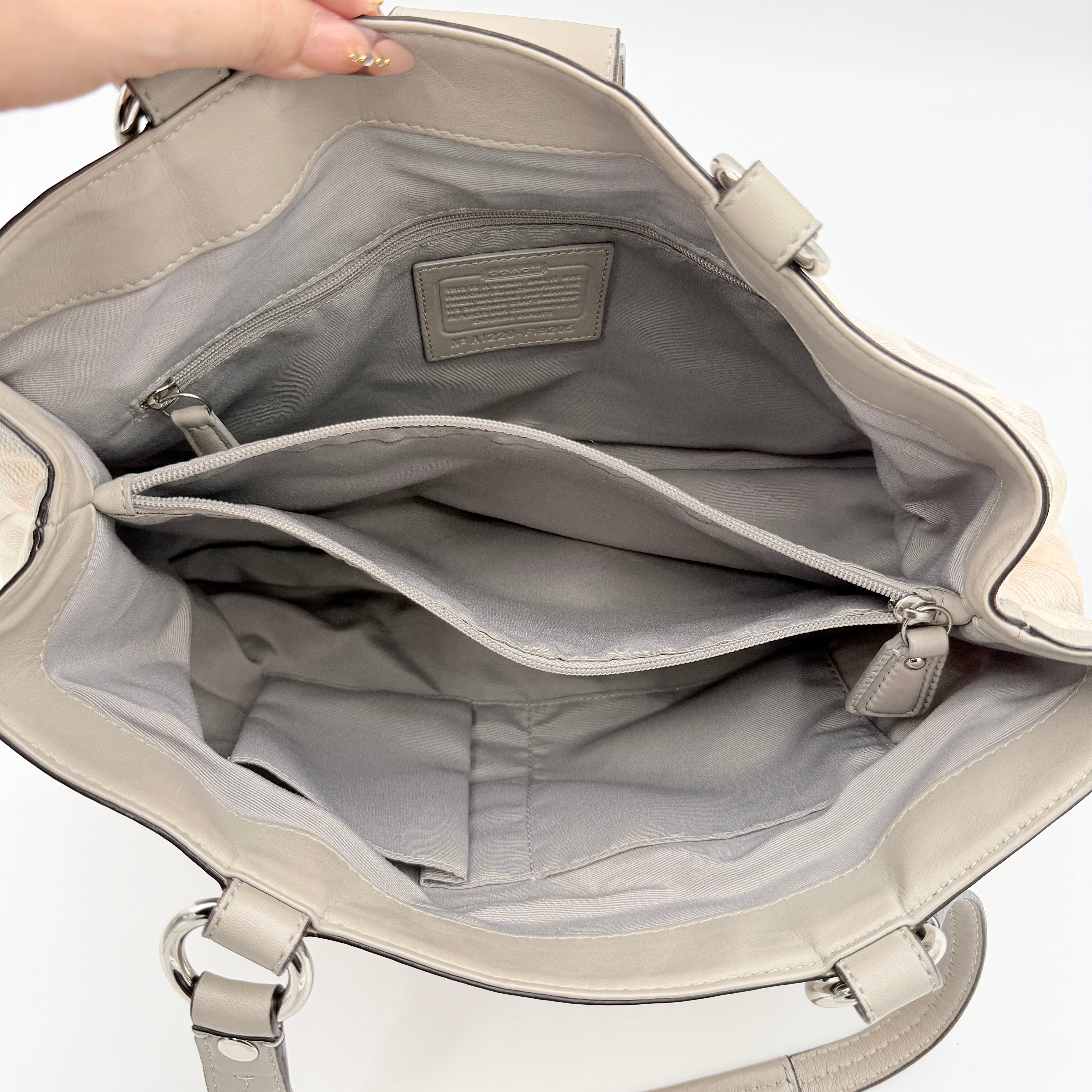 Coach Signature Optic Soho Shoulder Bag in grey and pink canvas with leather handles and buckle detail, shown against a white background.
