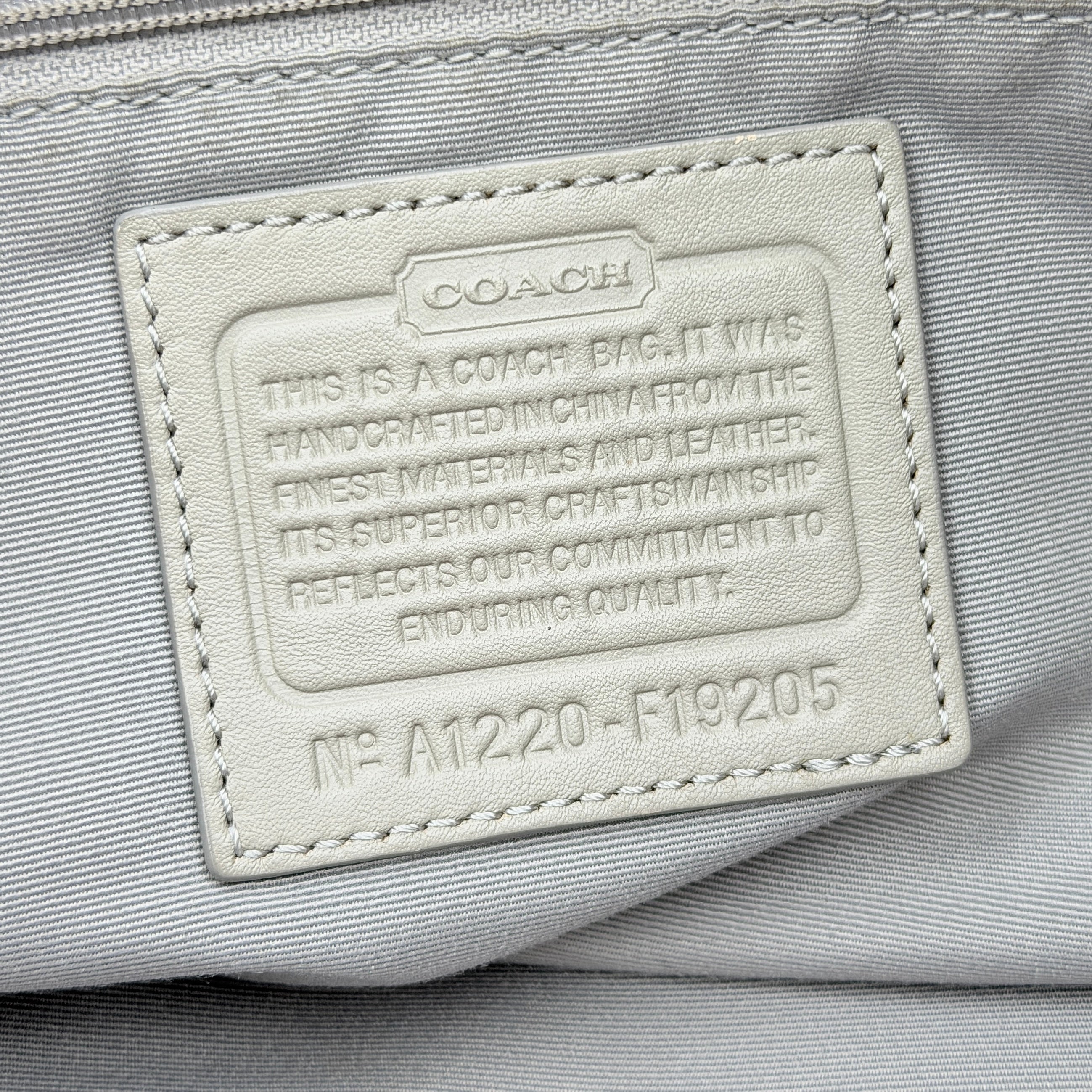 Coach Signature Optic Soho Shoulder Bag in grey and pink canvas with leather handles and buckle detail, shown against a white background.