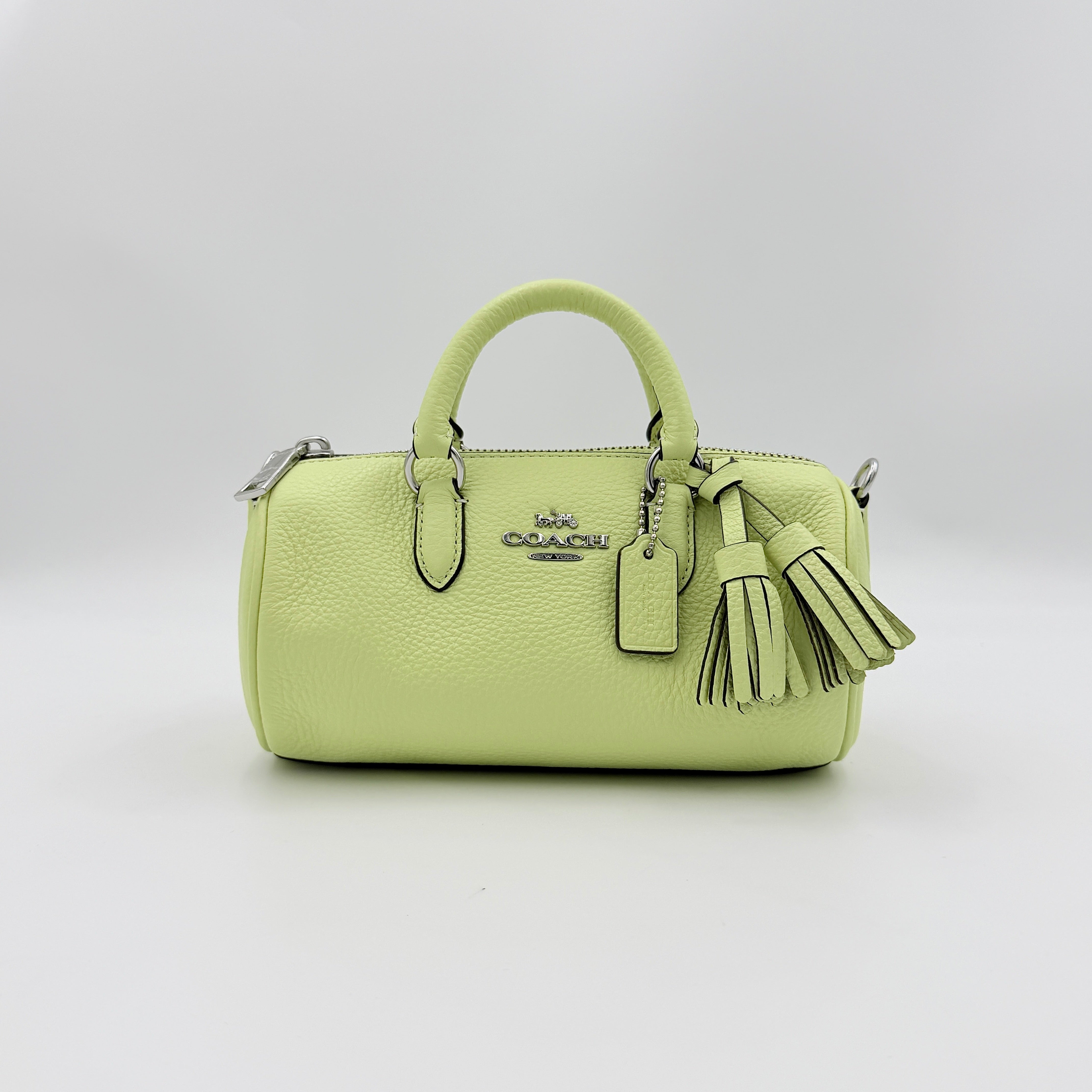Coach 2Way Lacey Mini Boston Bag in light green pebbled leather with tassels and a detachable strap, shown against a plain background.