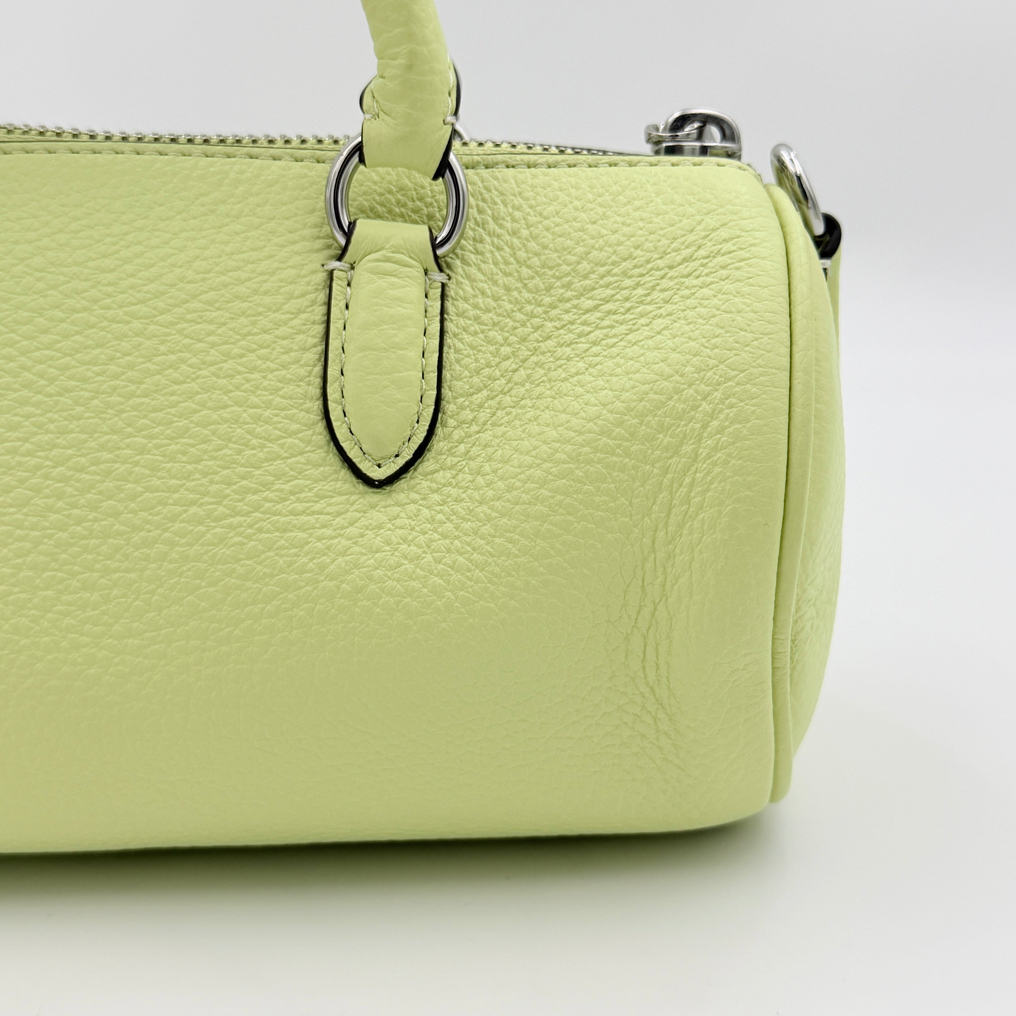 Coach 2Way Lacey Mini Boston Bag in light green pebbled leather with tassels and a detachable strap, shown against a plain background.