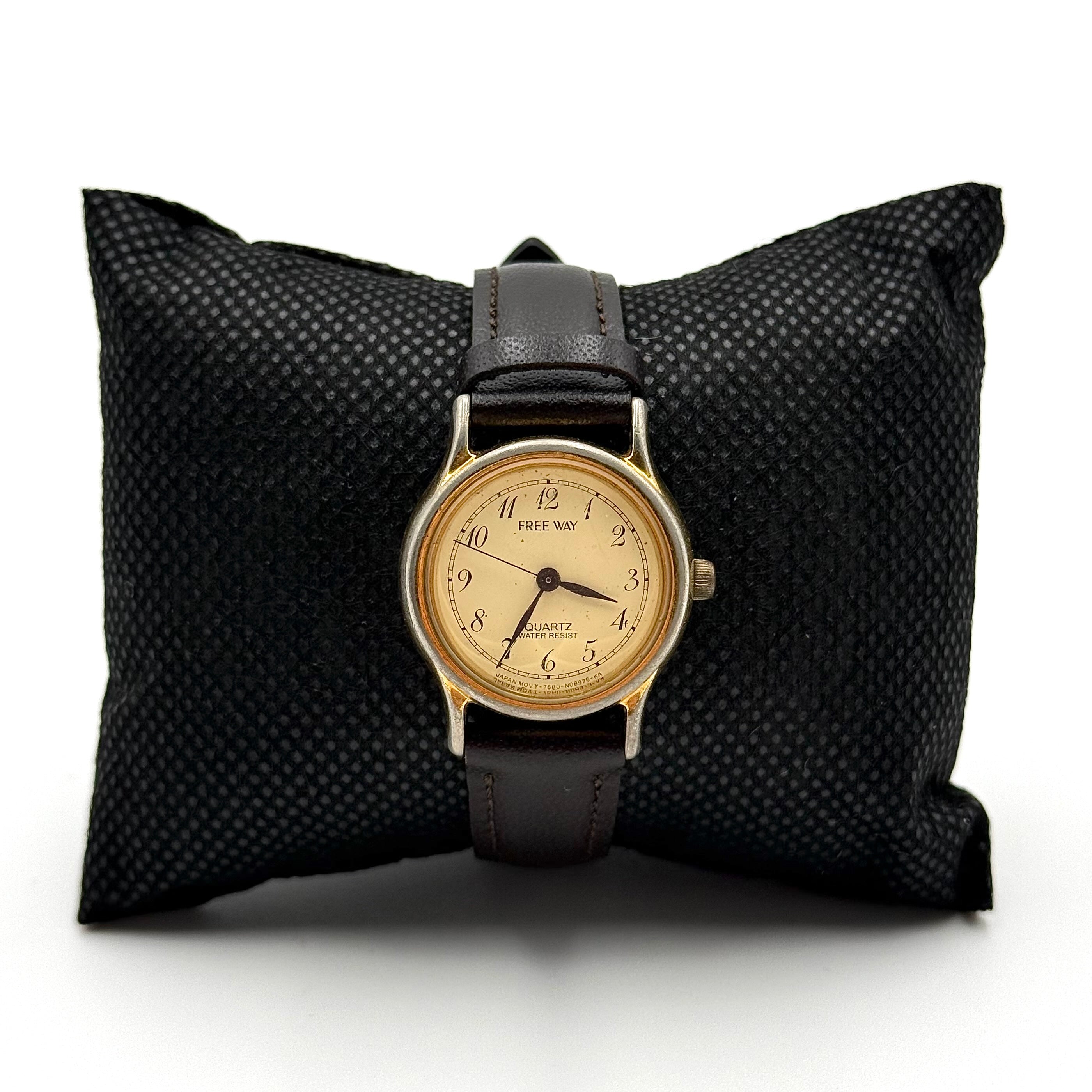 Citizen Freeway gold-tone quartz watch with black leather strap on a textured cushion