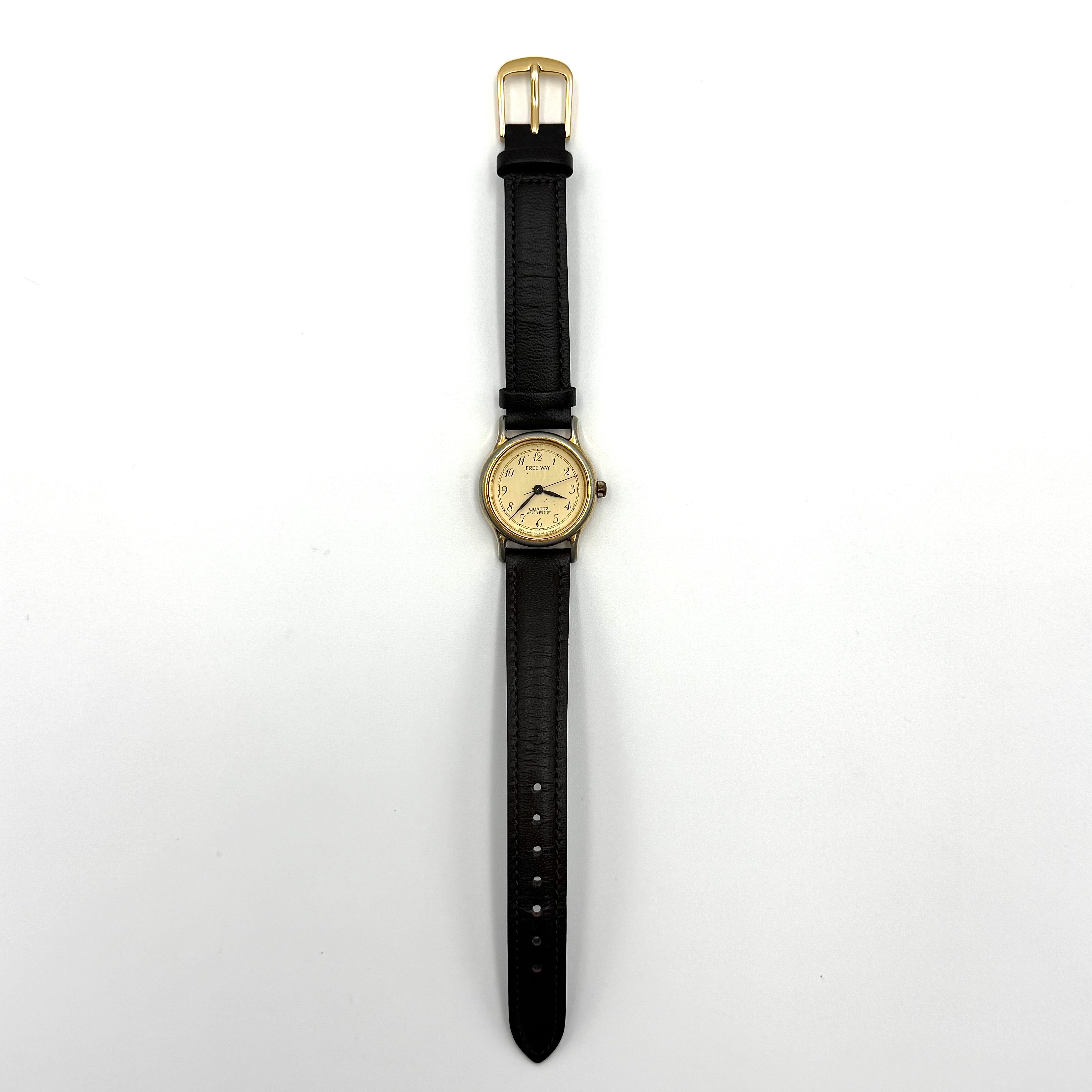 Citizen Freeway gold-tone quartz watch with black leather strap on a textured cushion