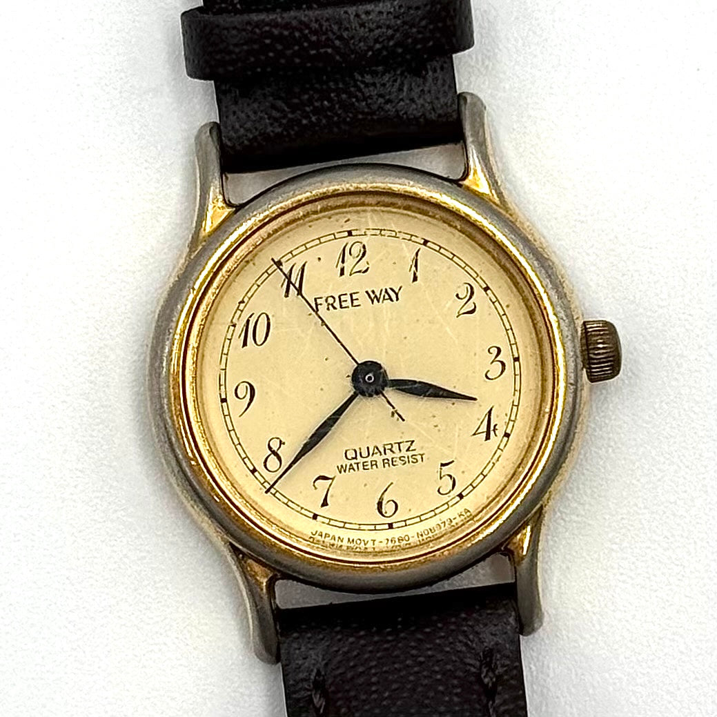 Citizen Freeway gold-tone quartz watch with black leather strap on a textured cushion