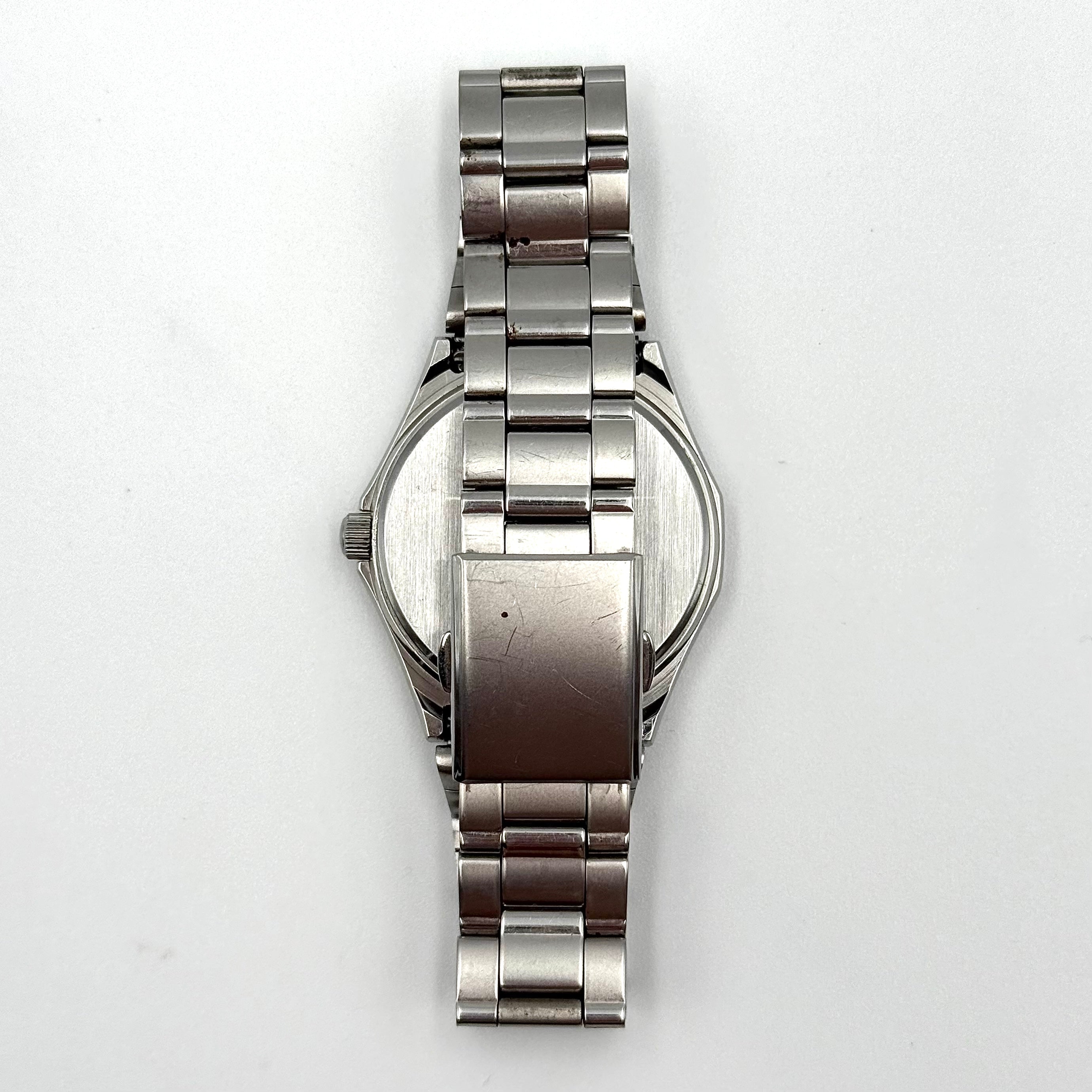Seiko Spirit 7N93-7000 Quartz Watch in silver with a white textured dial and stainless steel bracelet, shown on a black cushion.
