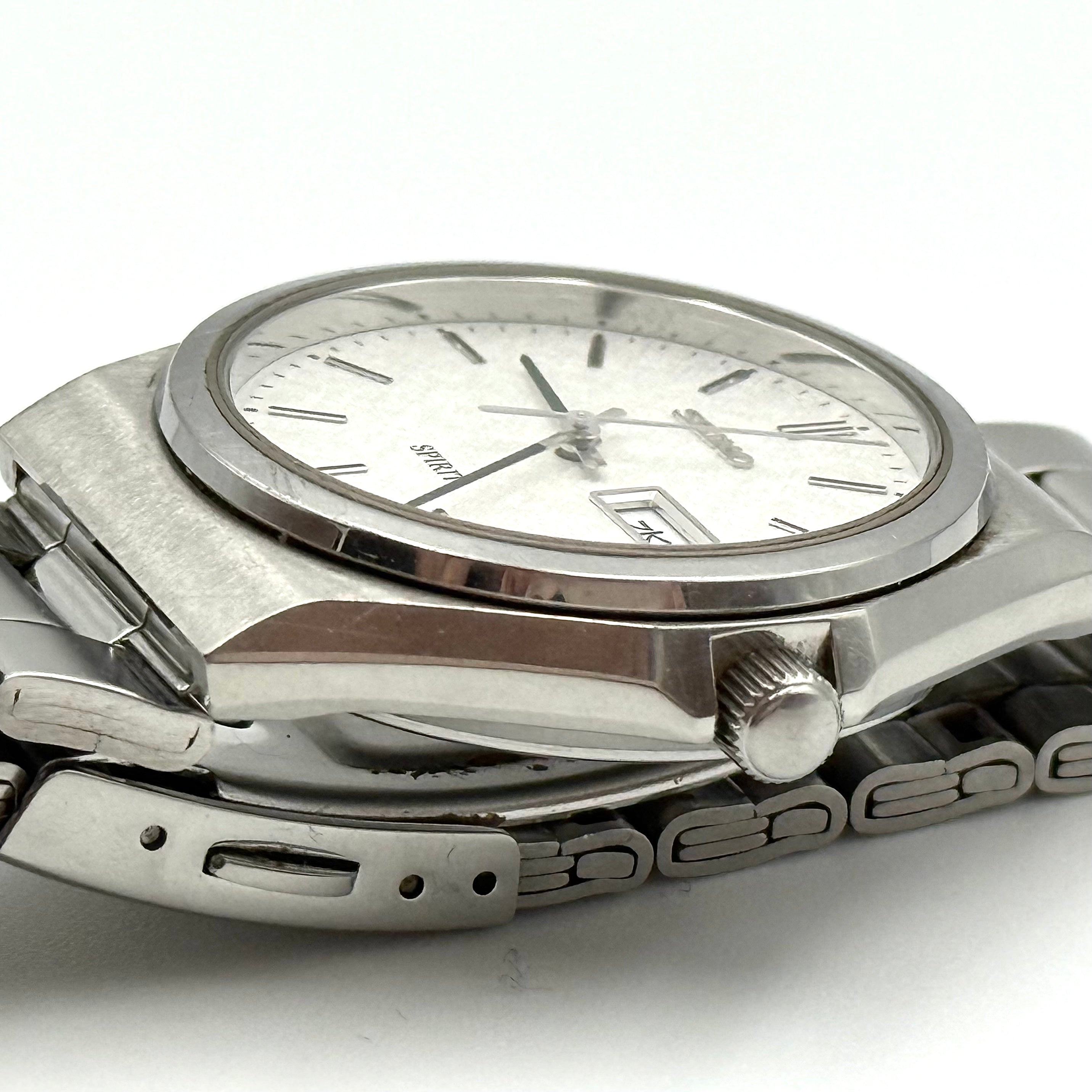 Seiko Spirit 7N93-7000 Quartz Watch in silver with a white textured dial and stainless steel bracelet, shown on a black cushion.