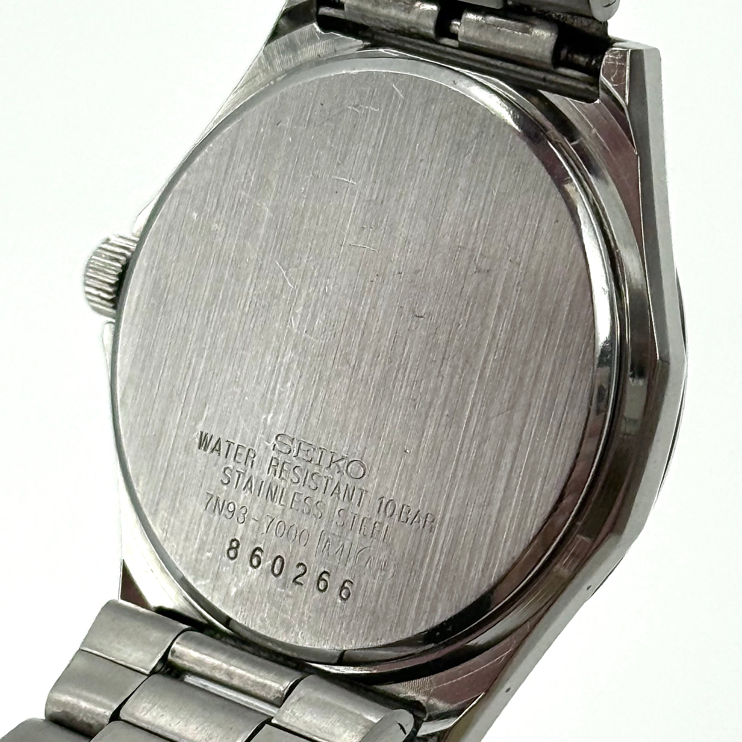 Seiko Spirit 7N93-7000 Quartz Watch in silver with a white textured dial and stainless steel bracelet, shown on a black cushion.