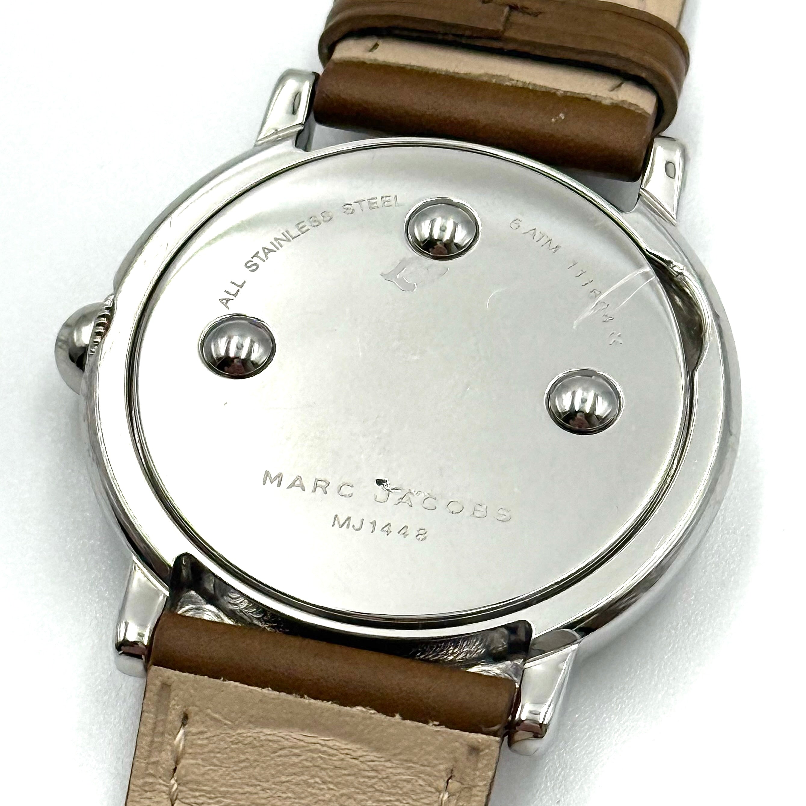 Marc Jacobs Courtney watch with silver stainless steel case and brown leather strap shown on a black cushion.