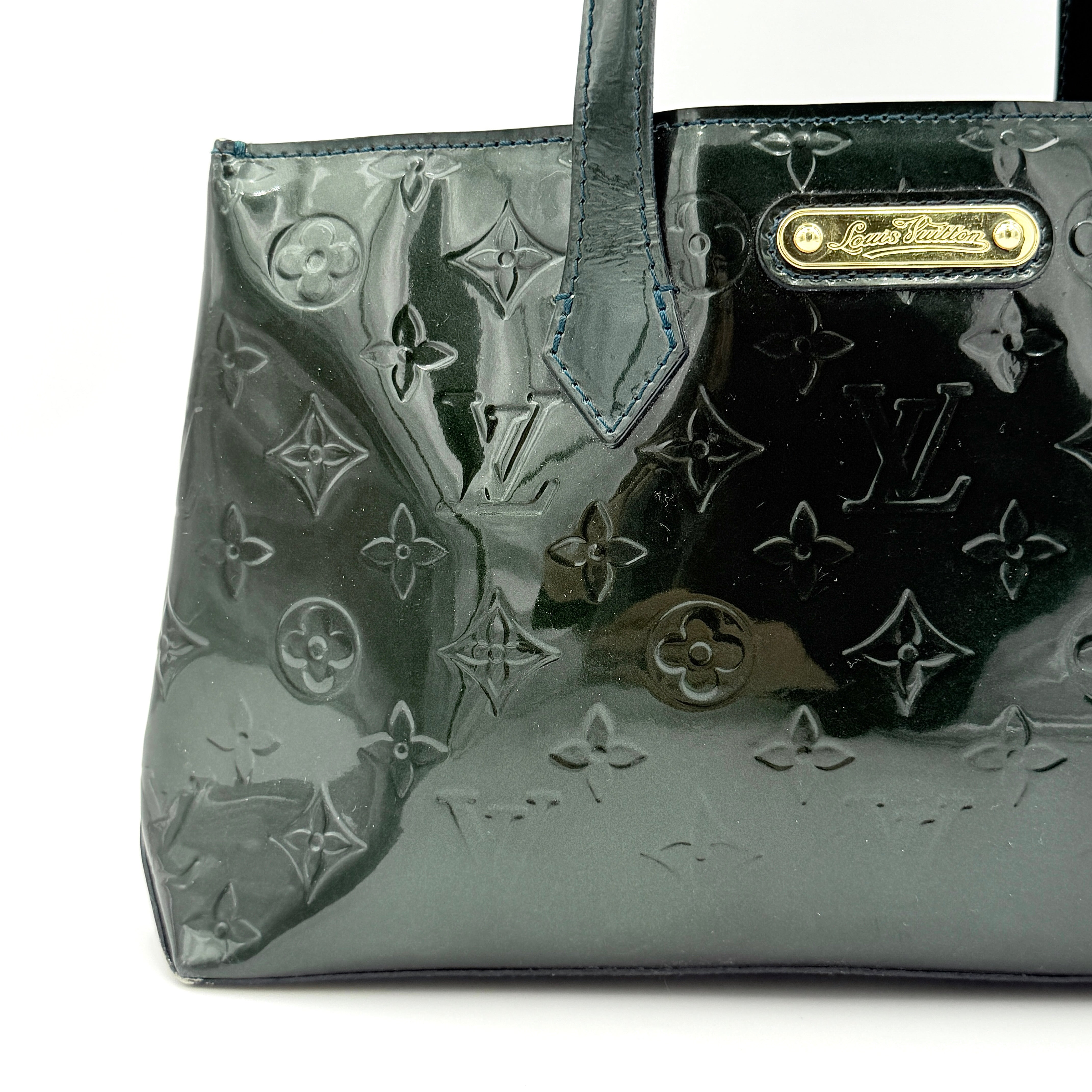 Louis Vuitton Wilshire PM bag in glossy dark green Monogram Vernis patent leather, shown with double top handles and gold-tone nameplate.