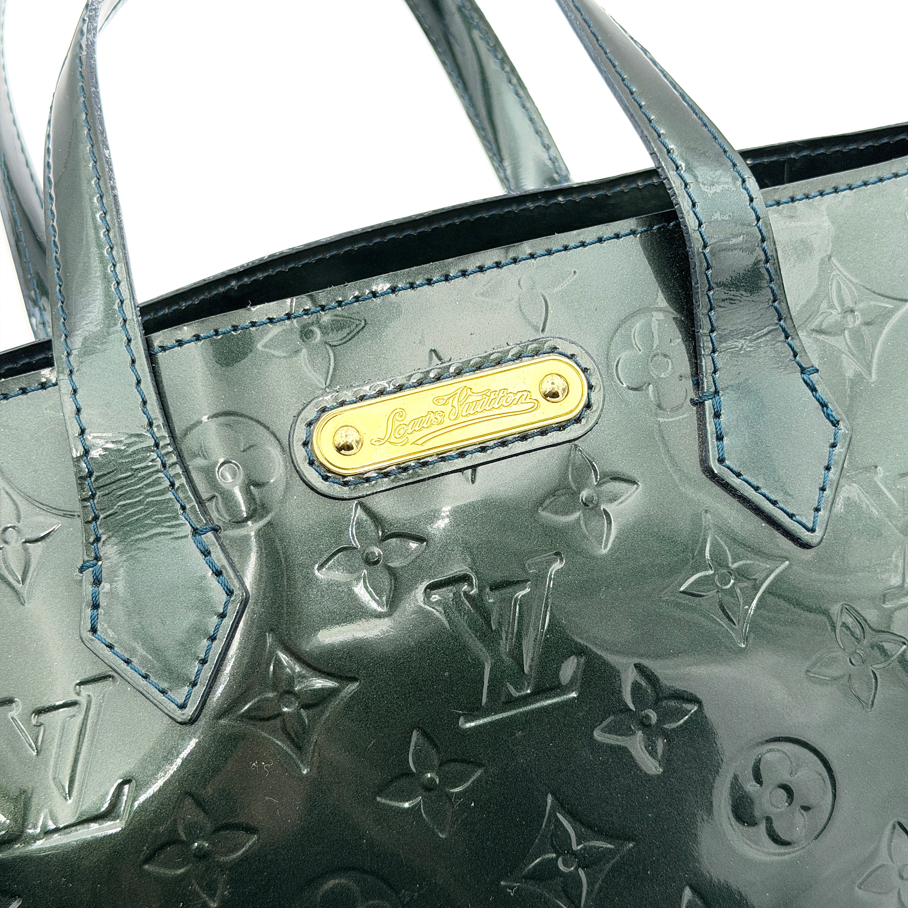 Louis Vuitton Wilshire PM bag in glossy dark green Monogram Vernis patent leather, shown with double top handles and gold-tone nameplate.