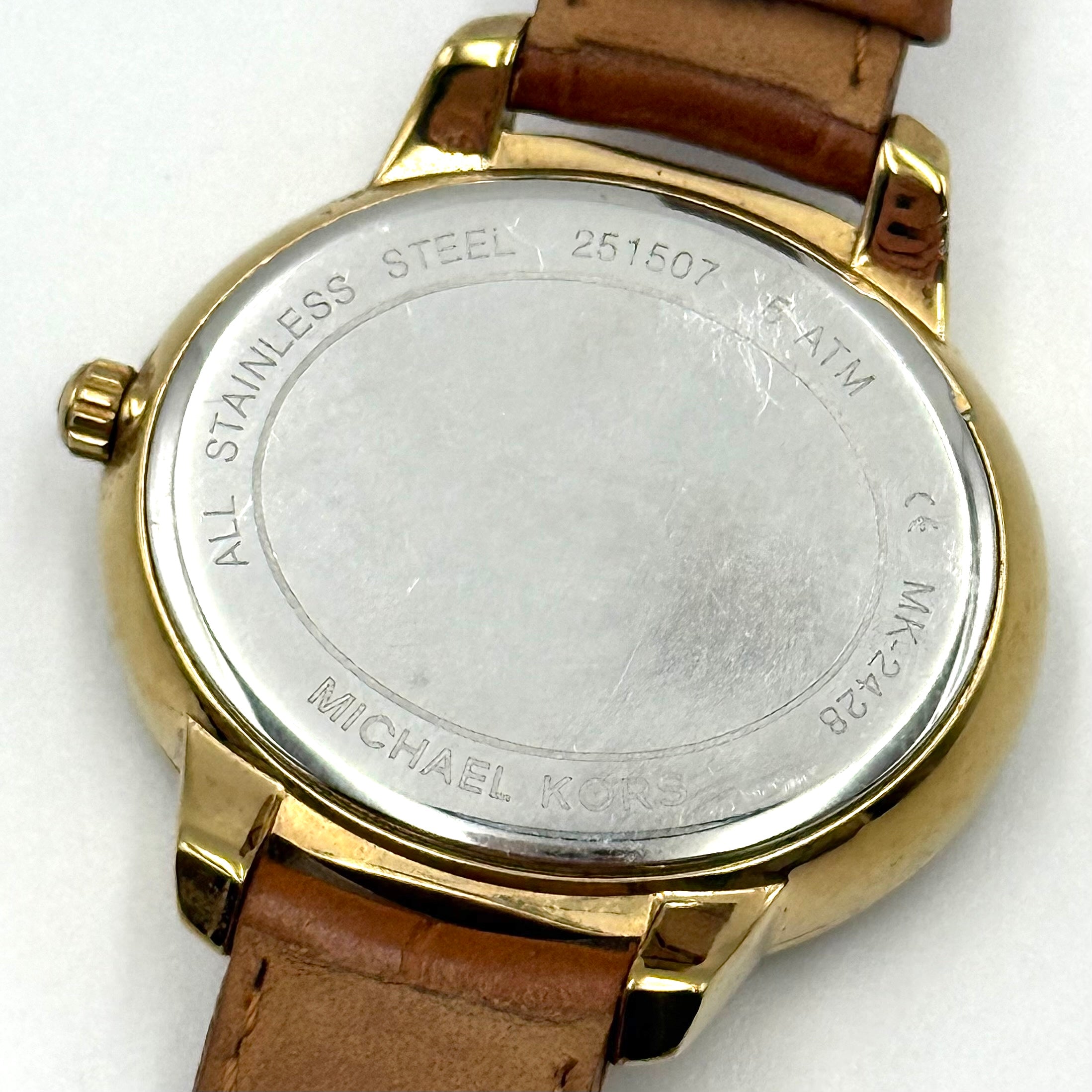 Michael Kors Whitley MK2428 watch with gold dial, crystal bezel and brown leather strap on black cushion