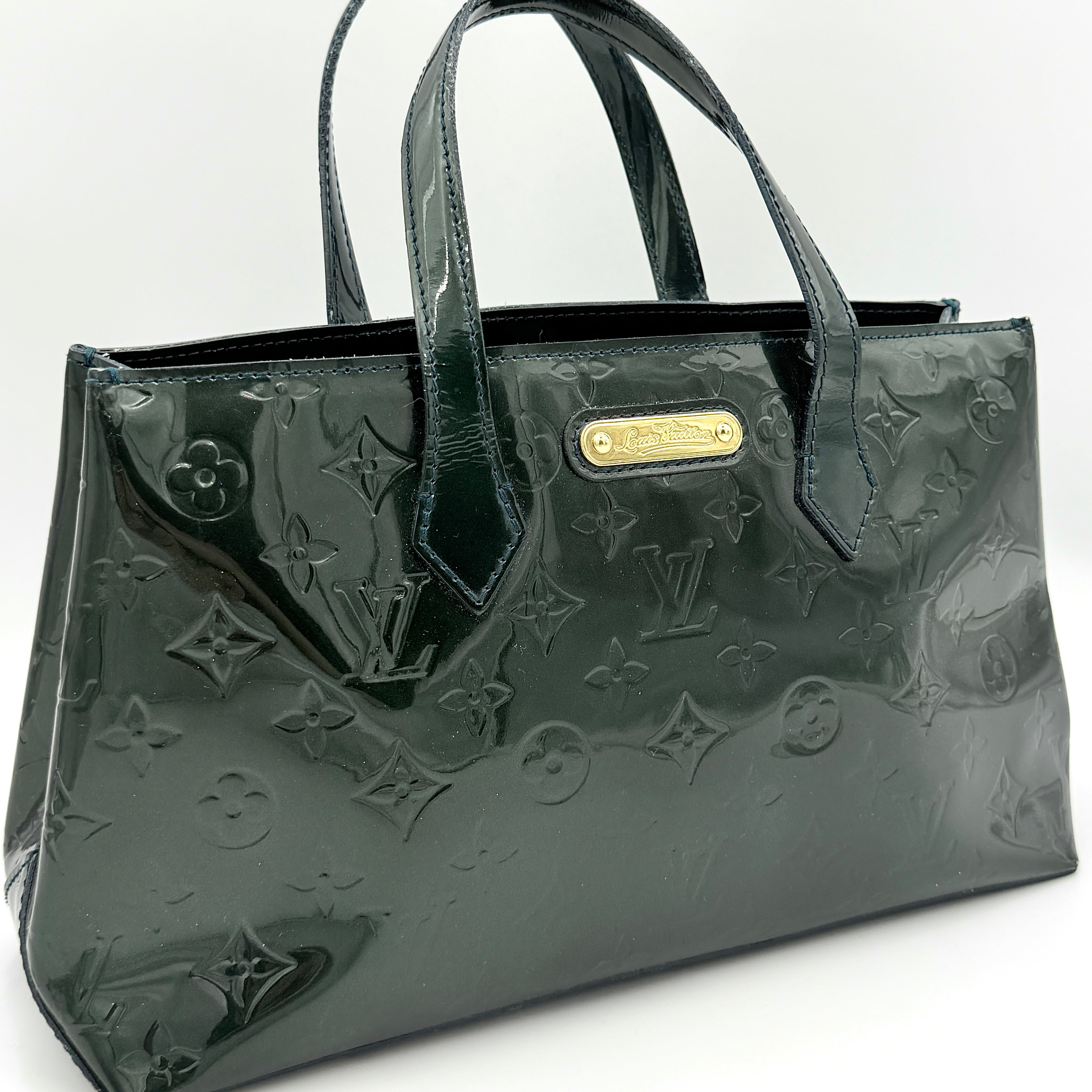Louis Vuitton Wilshire PM bag in glossy dark green Monogram Vernis patent leather, shown with double top handles and gold-tone nameplate.