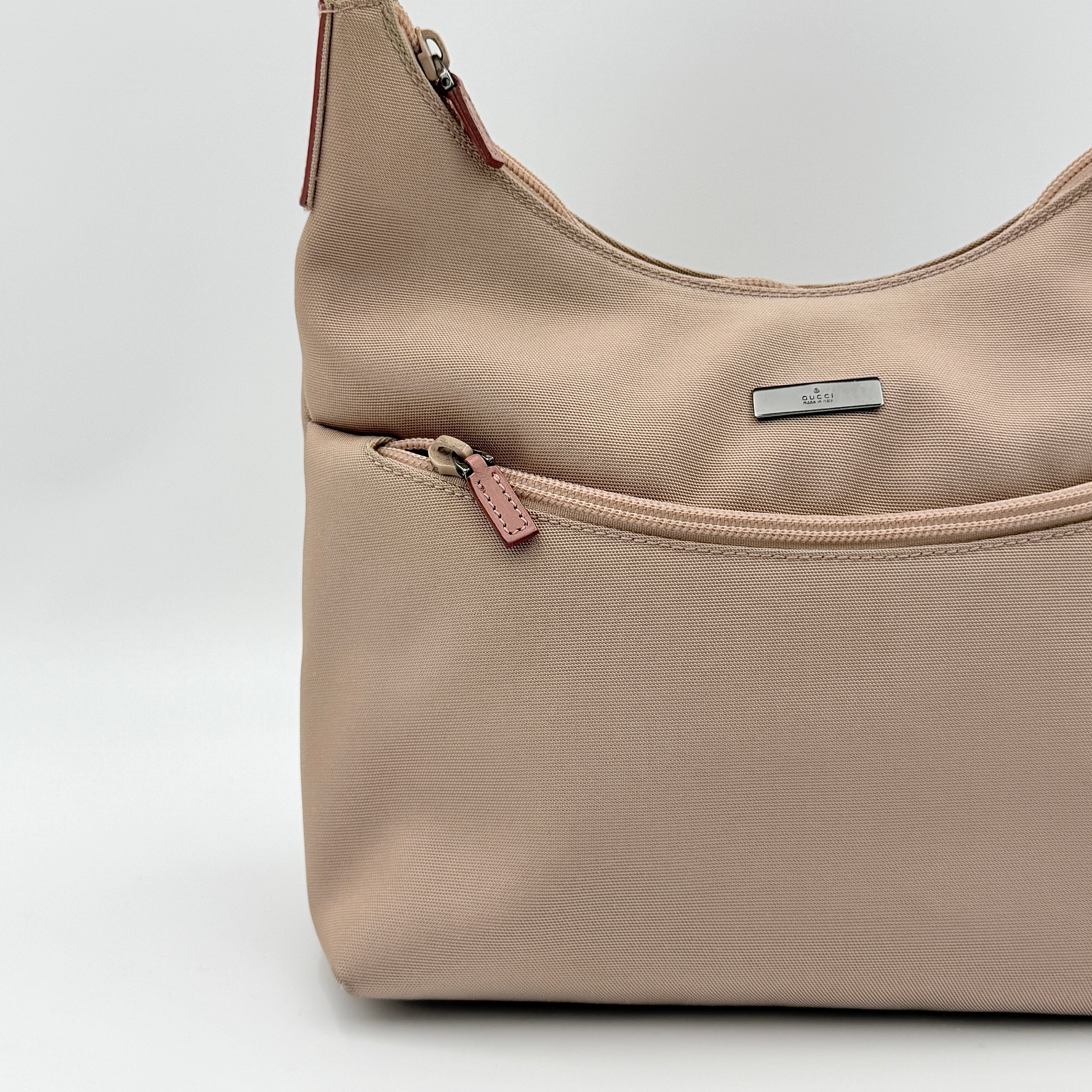 Gucci beige canvas hobo shoulder bag with pink leather accents and silver-tone hardware, displayed front-facing on a white background.