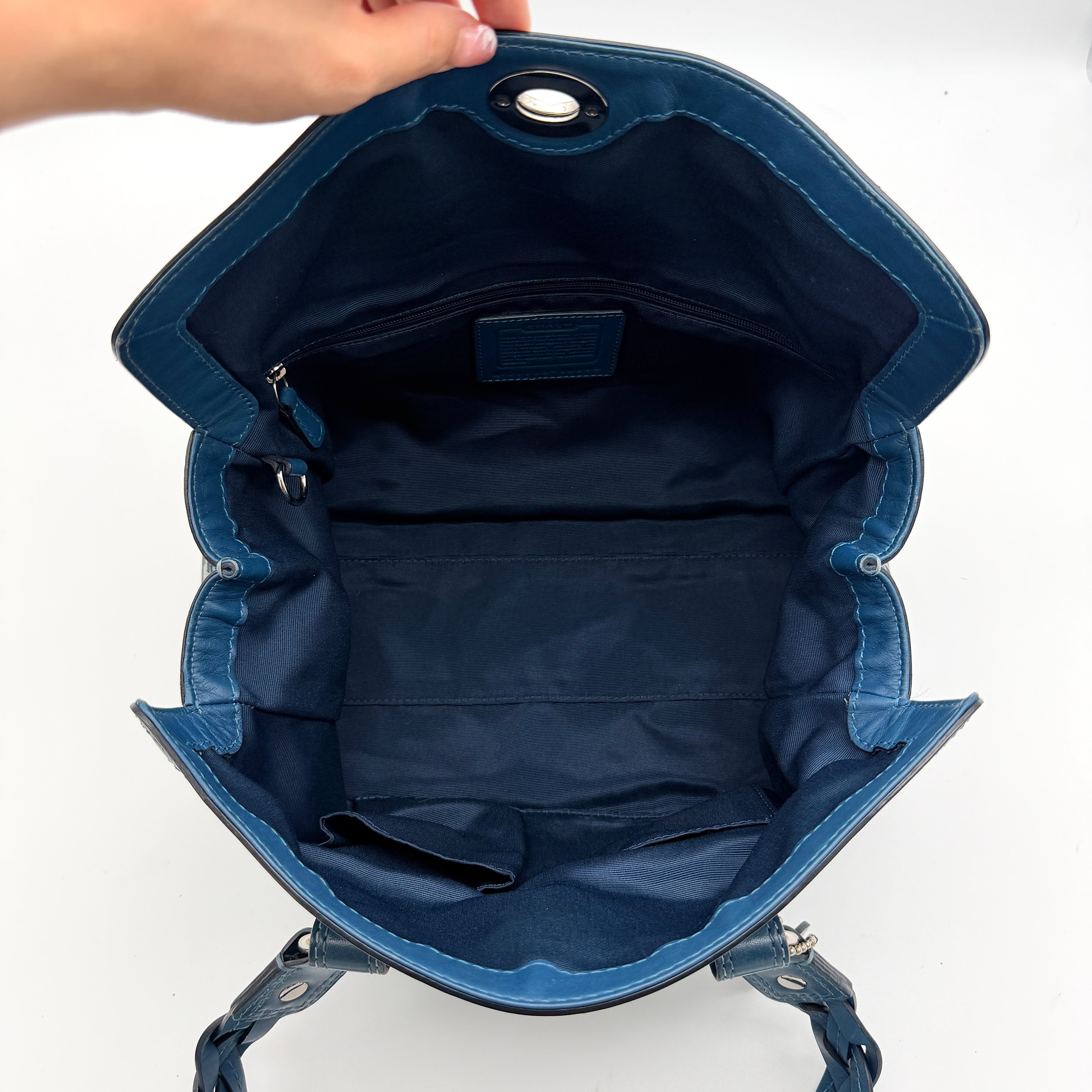 Coach Signature Chelsea Optic Satchel in blue canvas with leather braided handles and silver hardware, displayed on a Coach dust bag.
