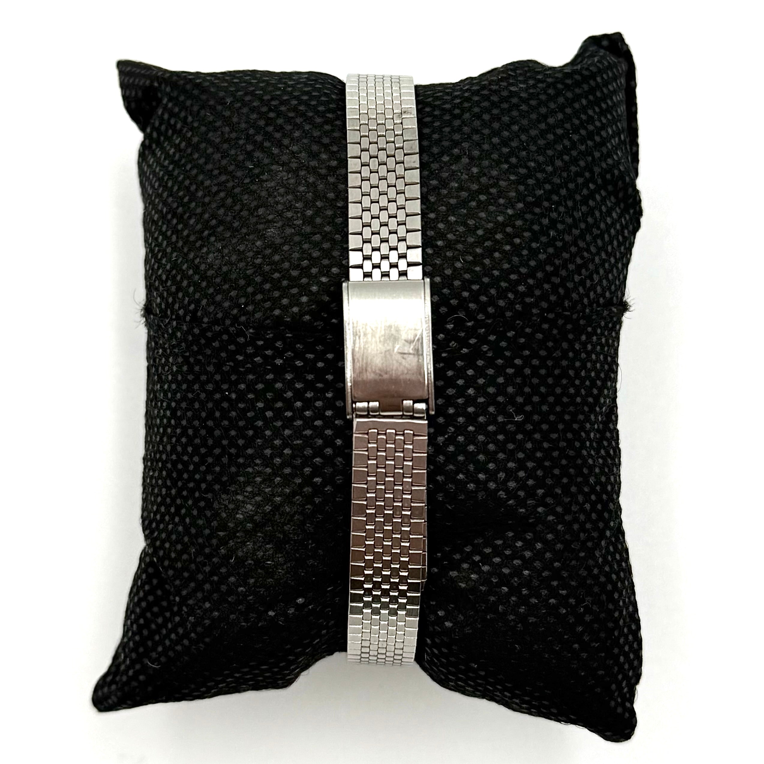 Seiko 7903-0030 Quartz stainless steel watch with a white textured dial and matching steel bracelet on a display pillow.