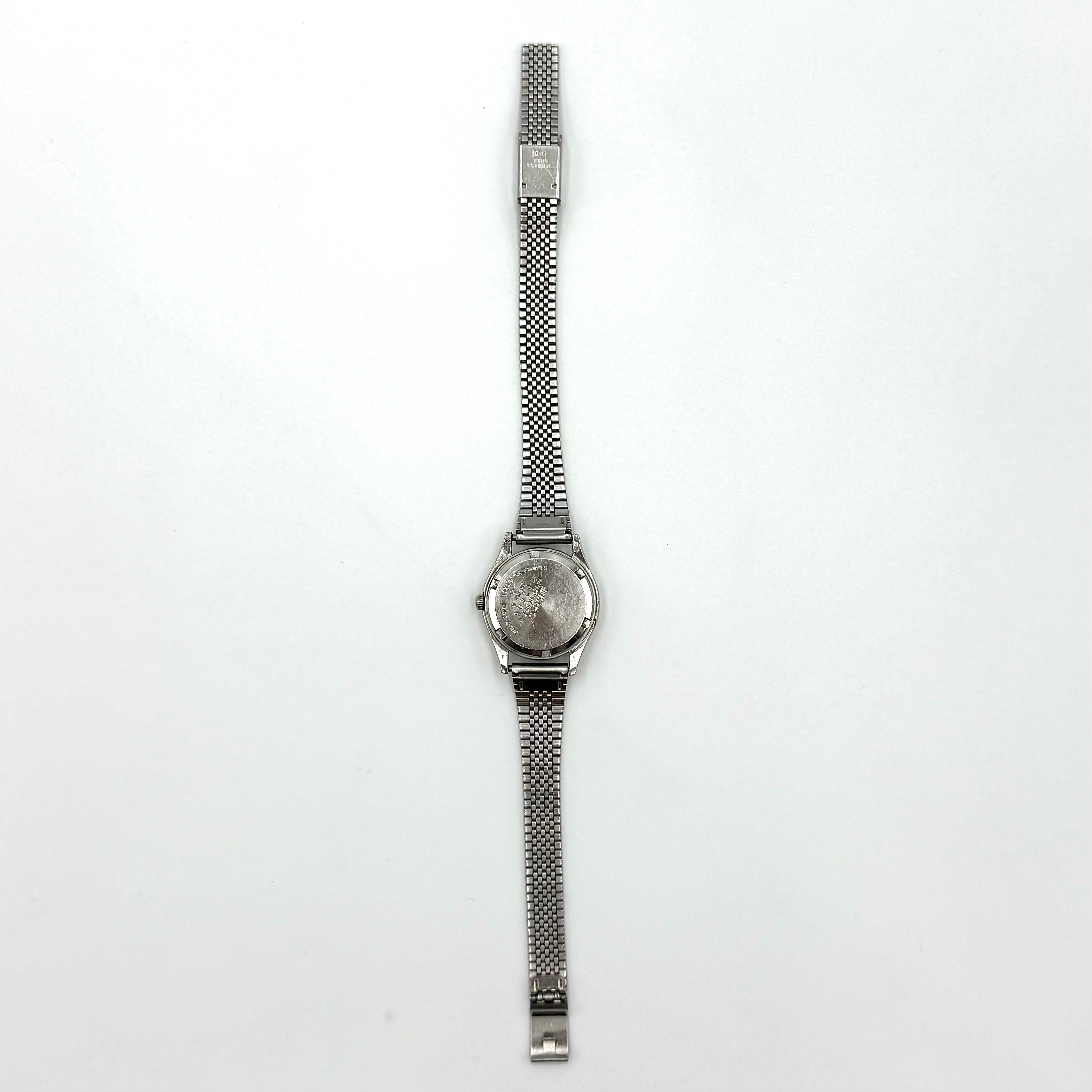 Seiko 7903-0030 Quartz stainless steel watch with a white textured dial and matching steel bracelet on a display pillow.