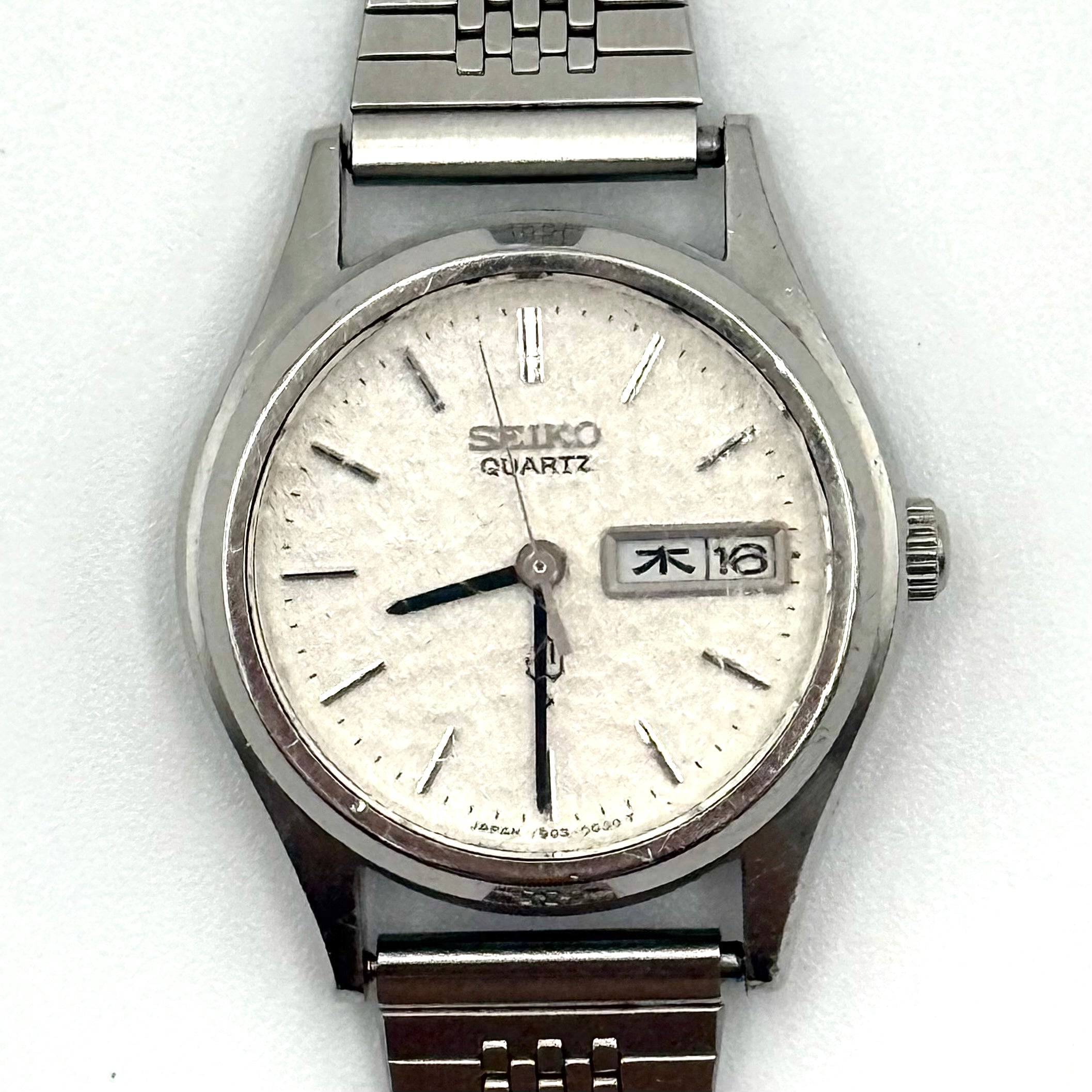 Seiko 7903-0030 Quartz stainless steel watch with a white textured dial and matching steel bracelet on a display pillow.