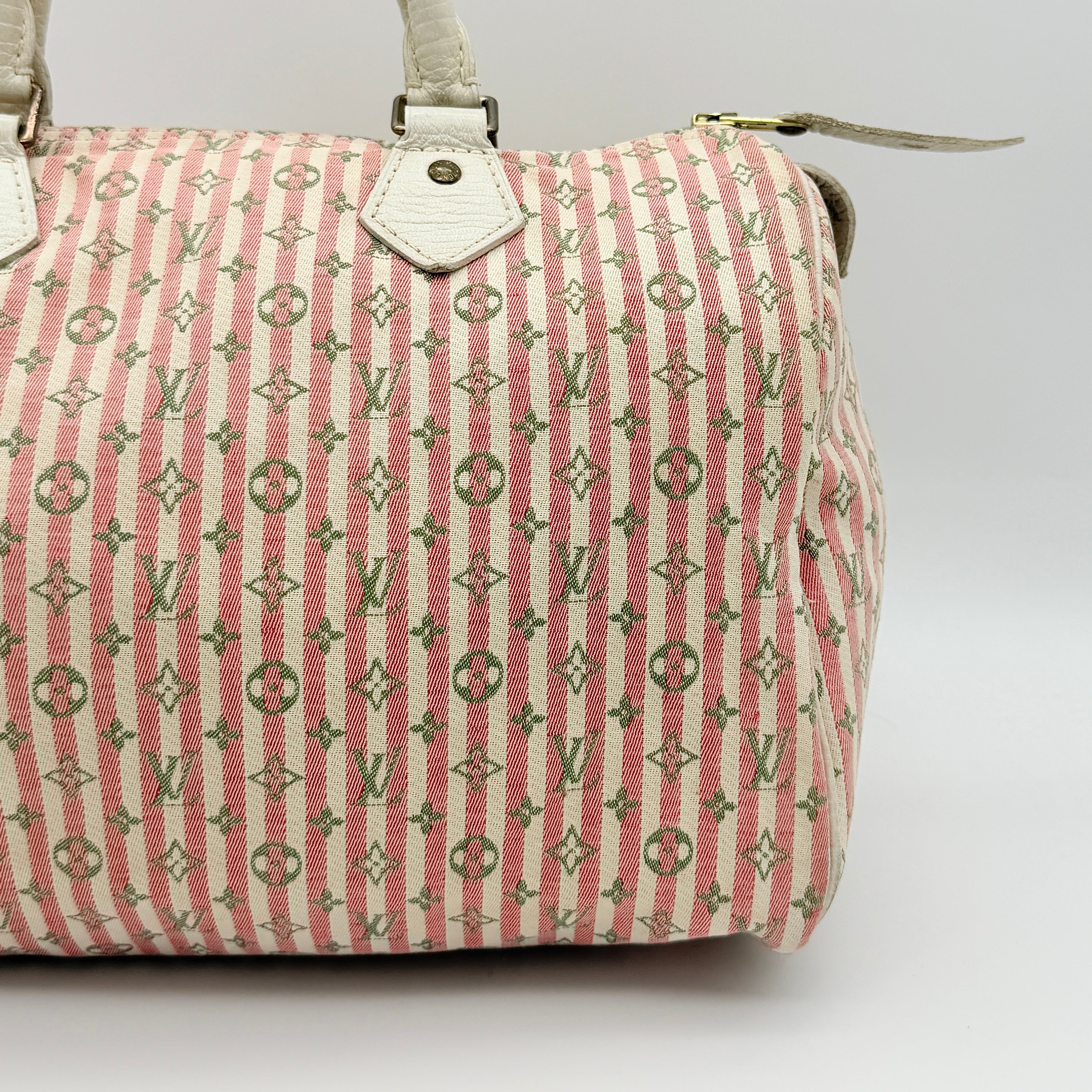 Louis Vuitton Speedy 30 in pink Mini Lin Monogram with cream leather handles and gold-tone zip, displayed on a neutral background.