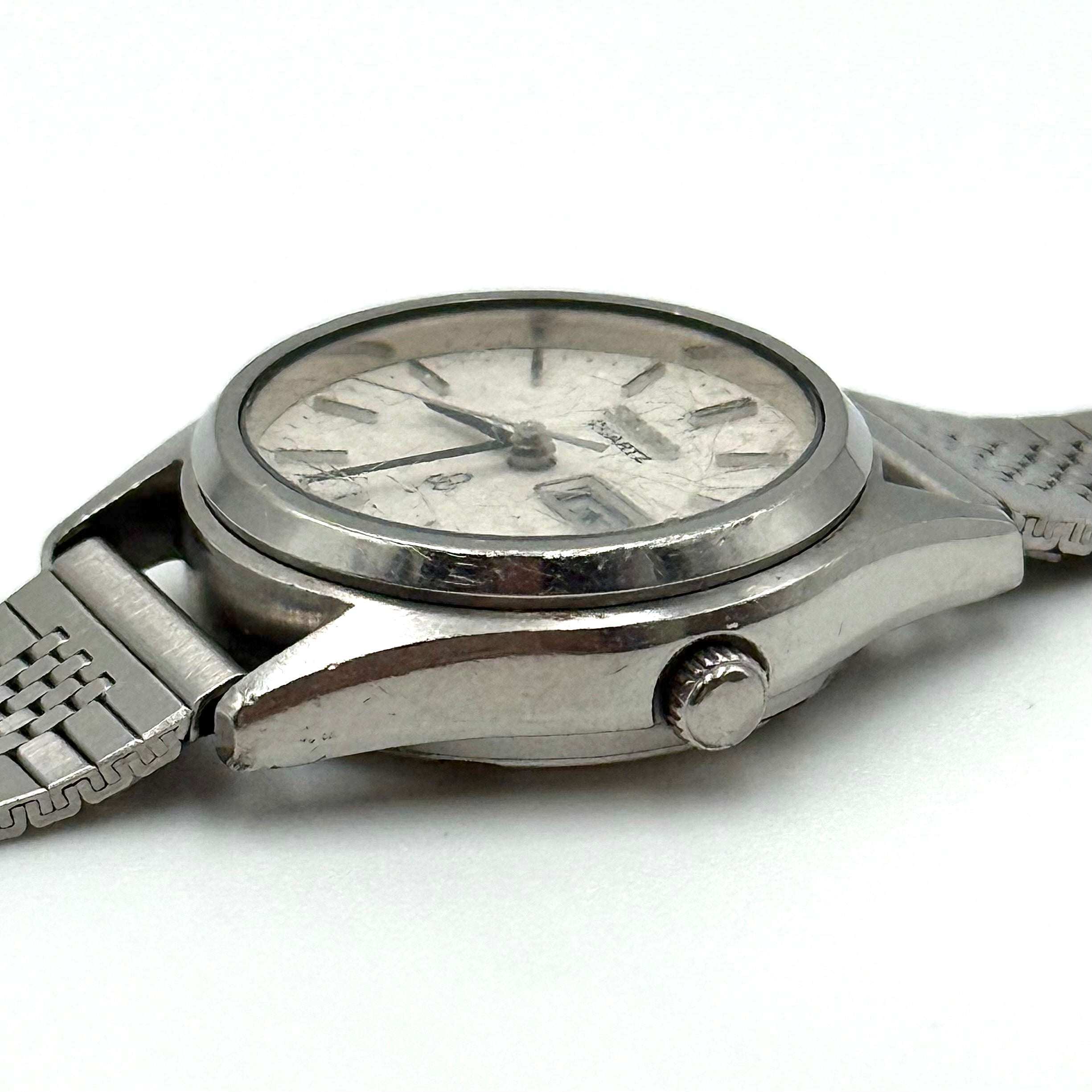 Seiko 7903-0030 Quartz stainless steel watch with a white textured dial and matching steel bracelet on a display pillow.
