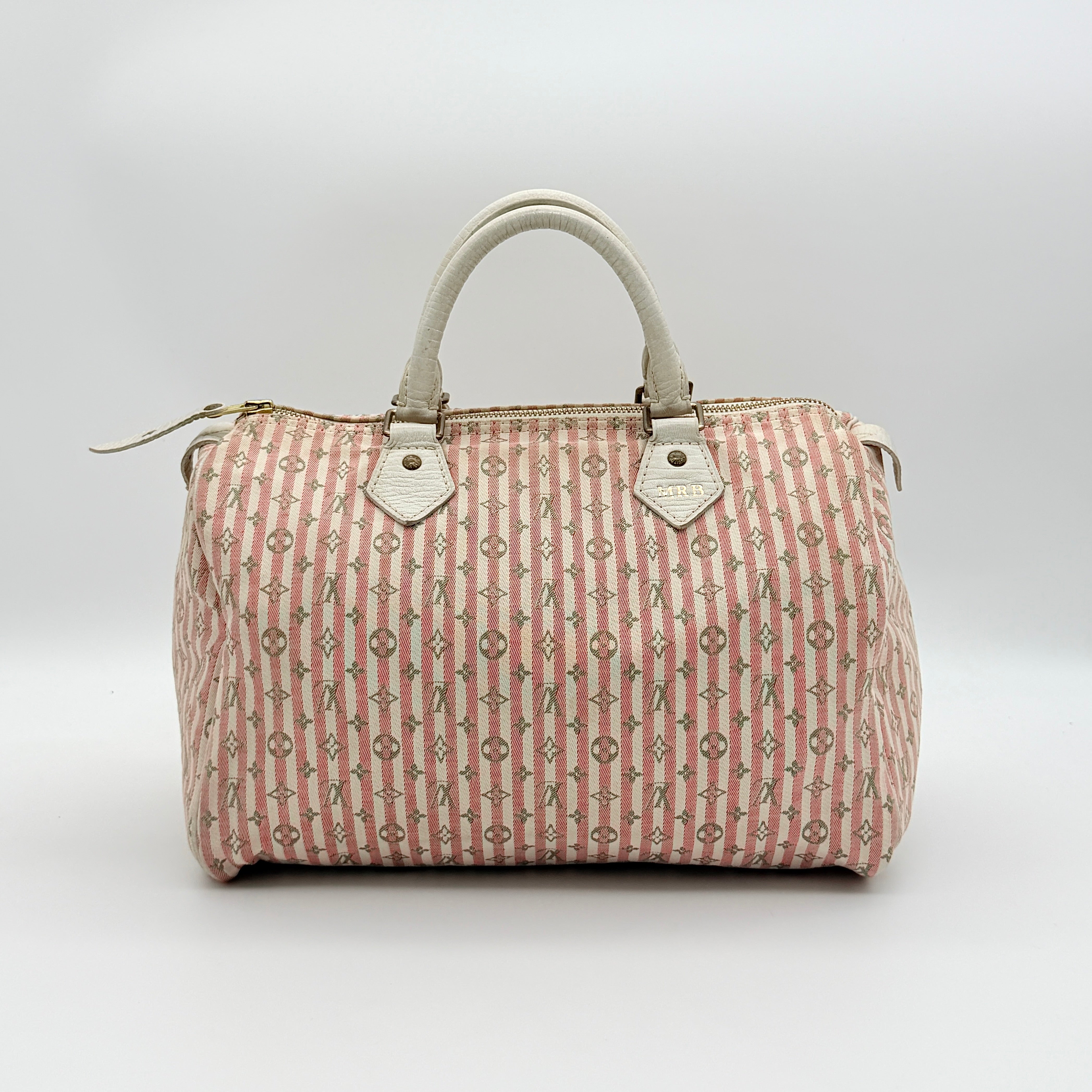 Louis Vuitton Speedy 30 in pink Mini Lin Monogram with cream leather handles and gold-tone zip, displayed on a neutral background.