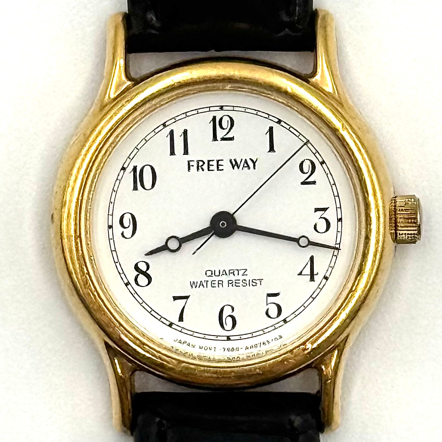 Citizen Freeway Quartz watch with white dial, gold case, and black leather strap displayed on a black cushion.