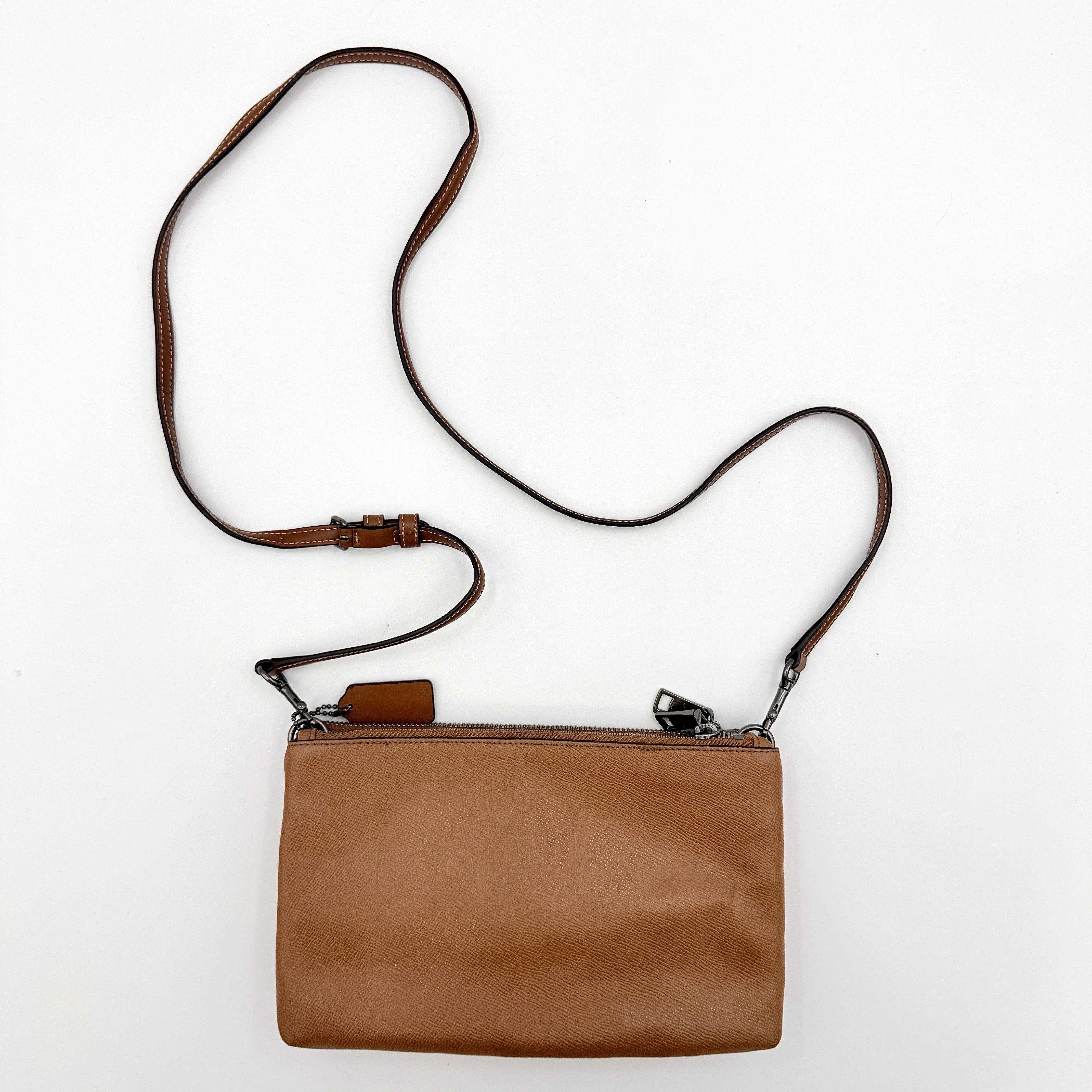 Coach x Keith Haring Lyla Crossbody bag in textured brown leather with bold pink graphic pattern and white artwork, featuring an adjustable strap.