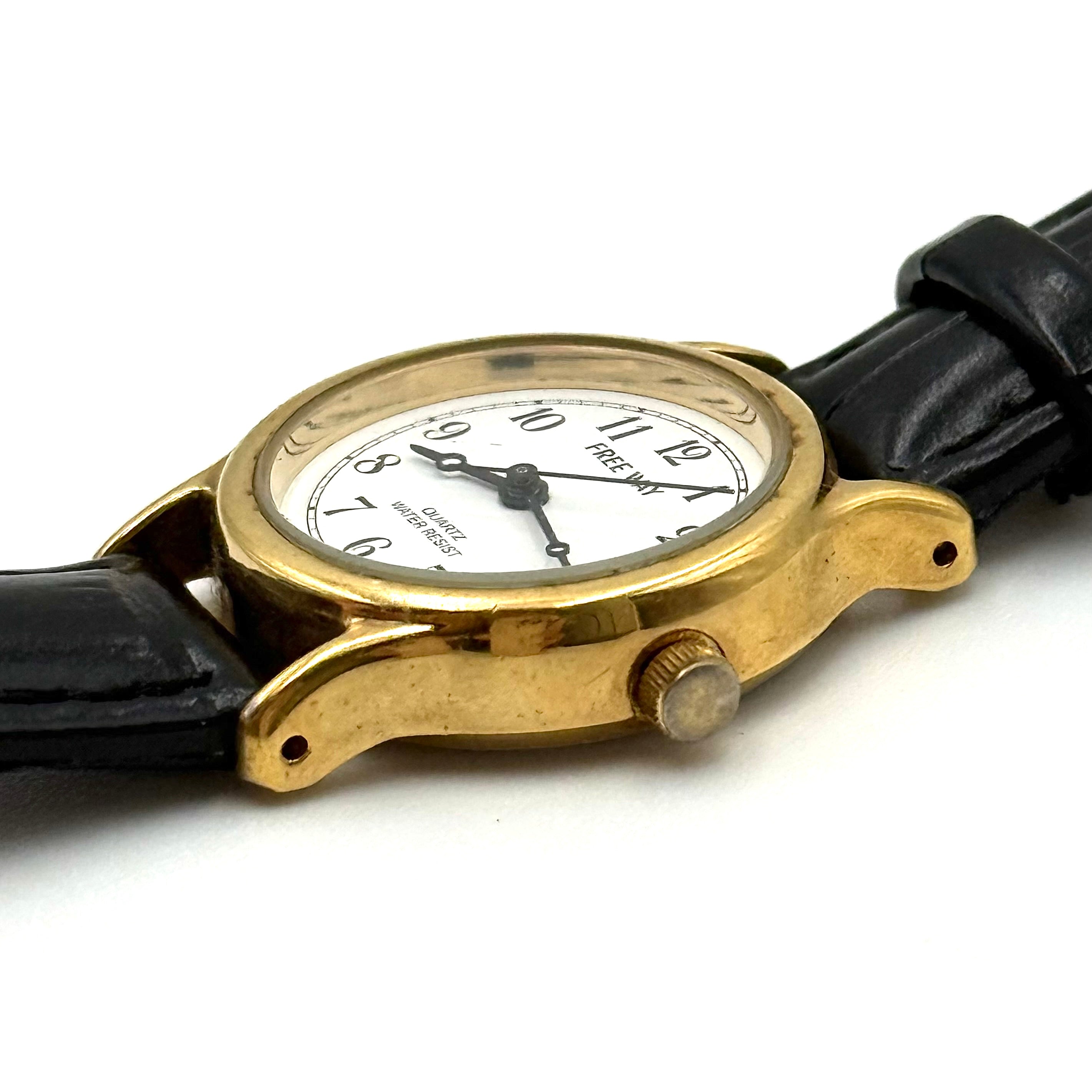 Citizen Freeway Quartz watch with white dial, gold case, and black leather strap displayed on a black cushion.