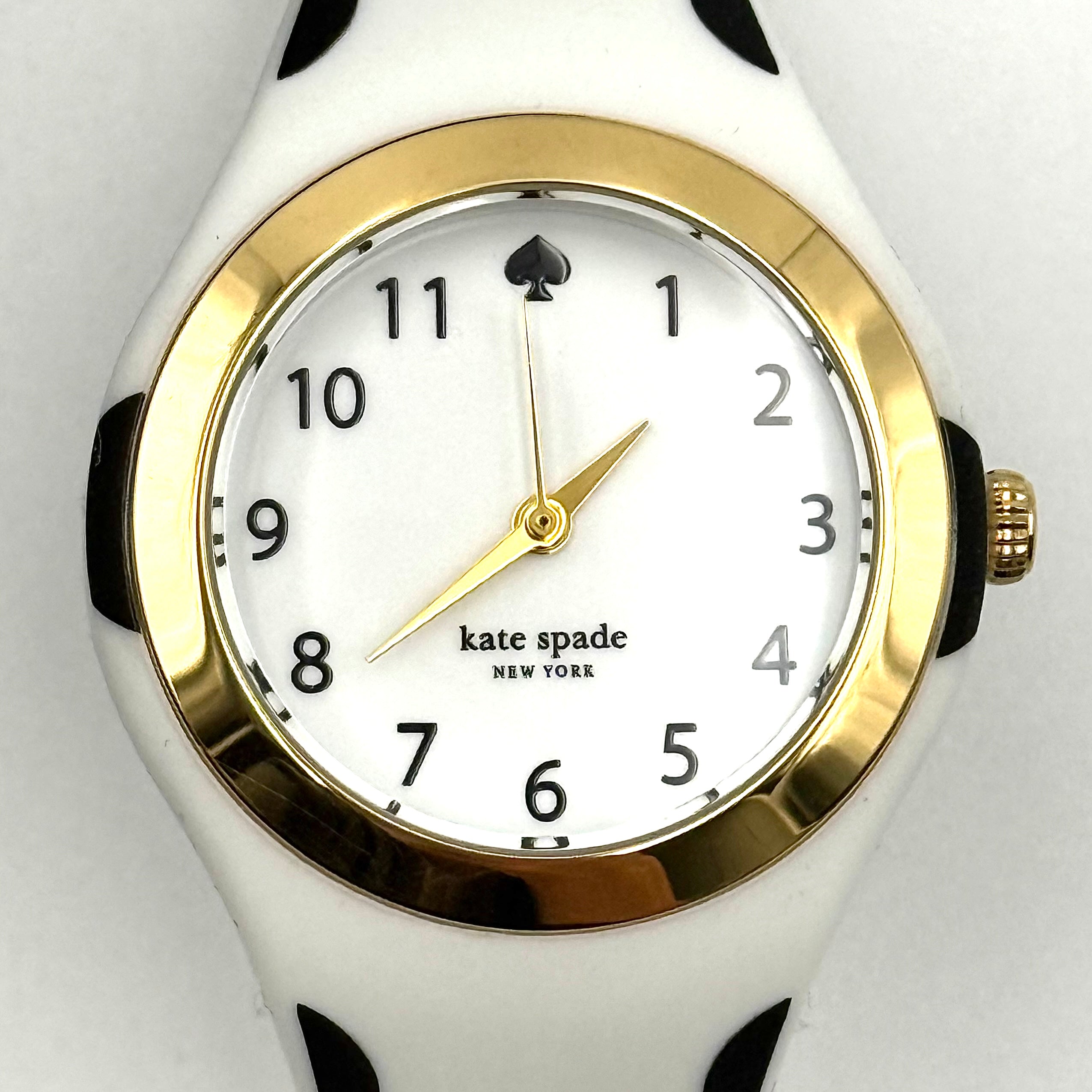Kate Spade New York Rumsey 0838 silicone watch in white with black polka dots, gold-tone bezel, and white dial displayed on a cushion.