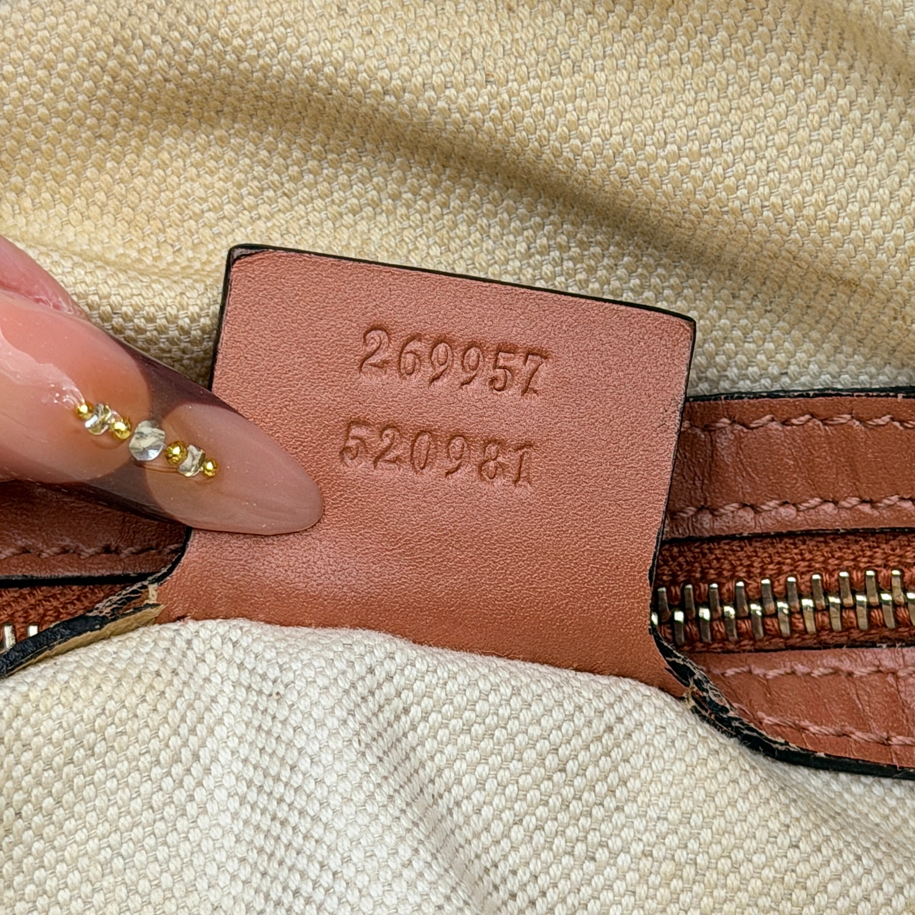 Gucci beige GG monogram shoulder bag with orange leather trim, heart bit charm, and detachable strap displayed on a white background.