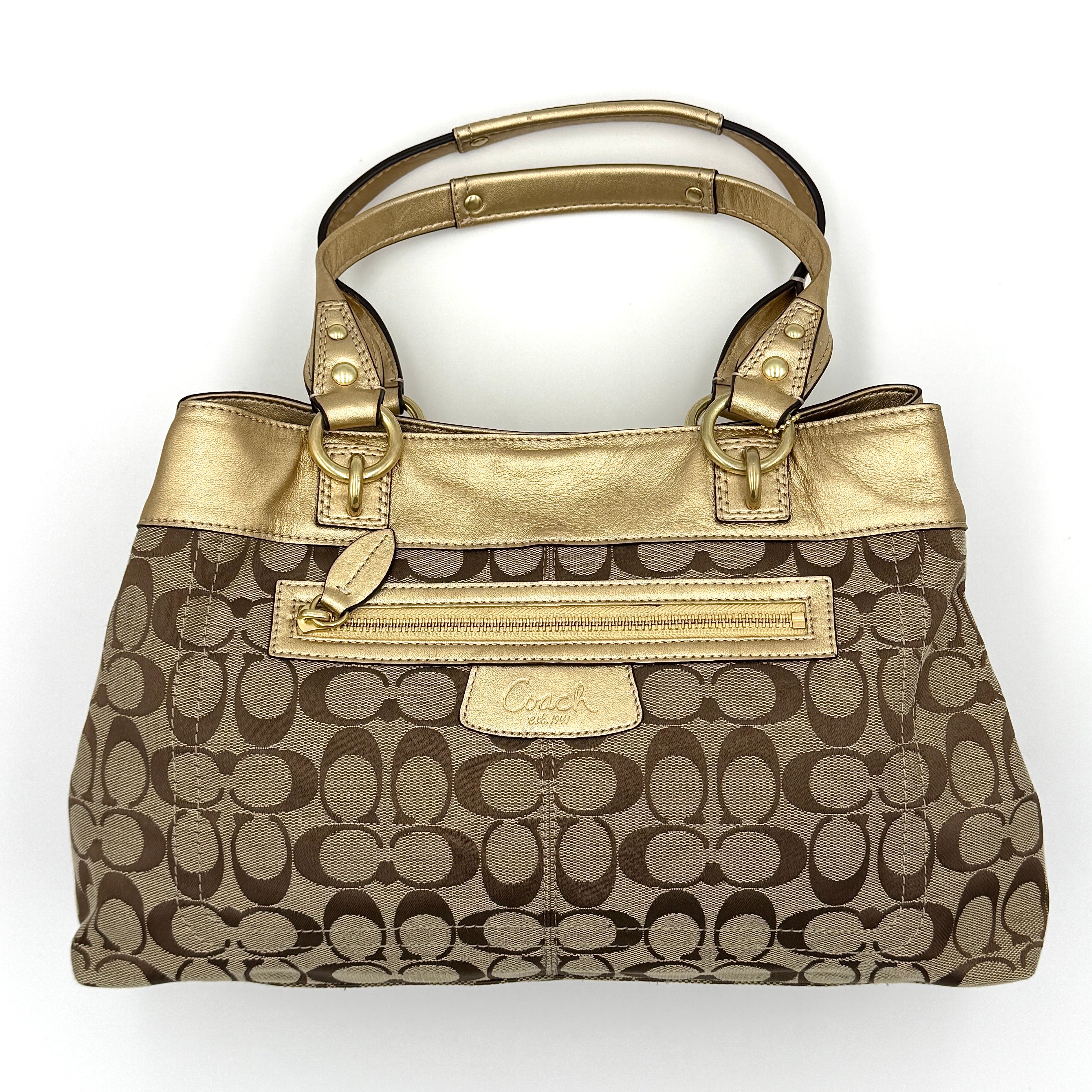 Coach Signature Penelope Shoulder Bag in beige monogram canvas with gold leather trim and gold-tone hardware displayed upright.