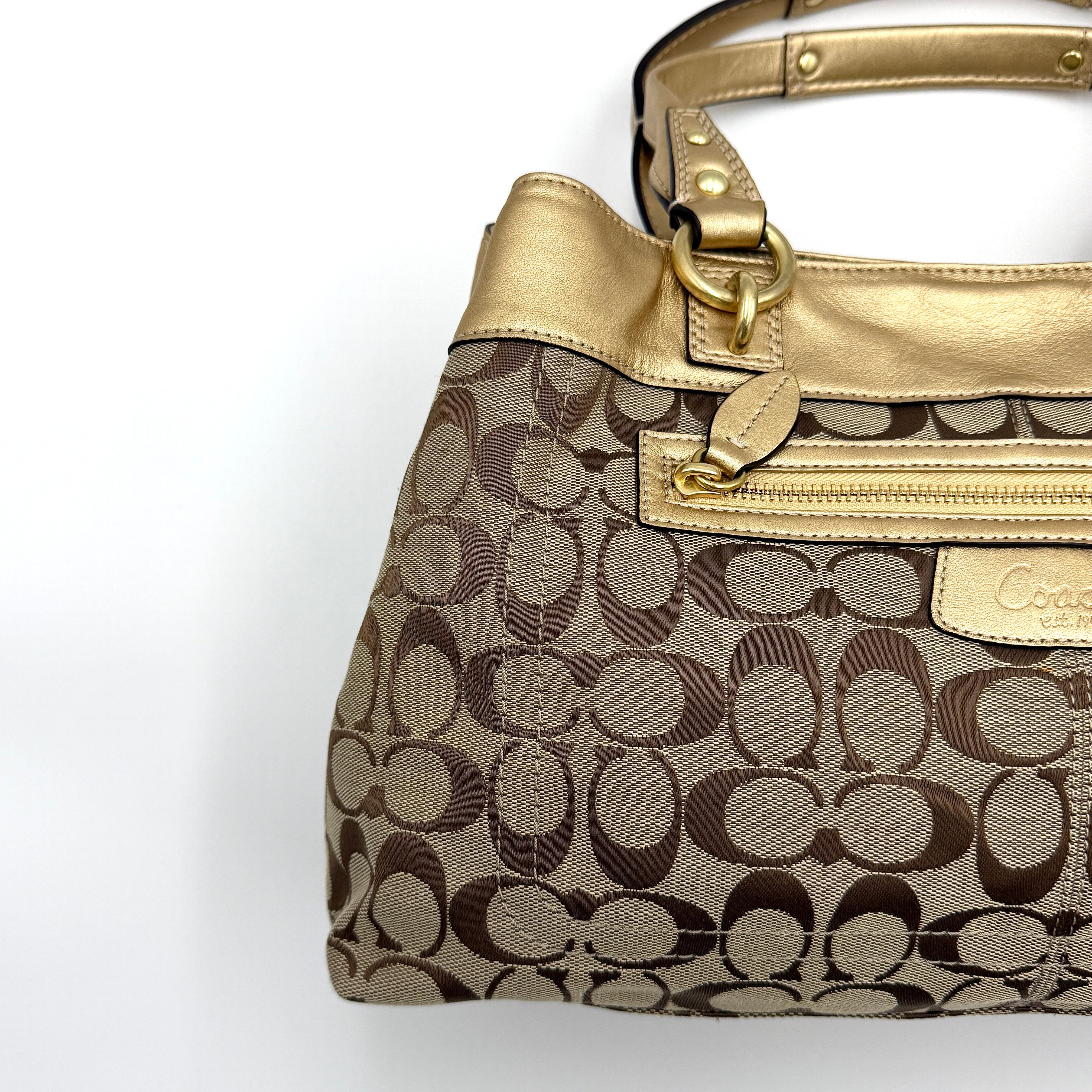 Coach Signature Penelope Shoulder Bag in beige monogram canvas with gold leather trim and gold-tone hardware displayed upright.