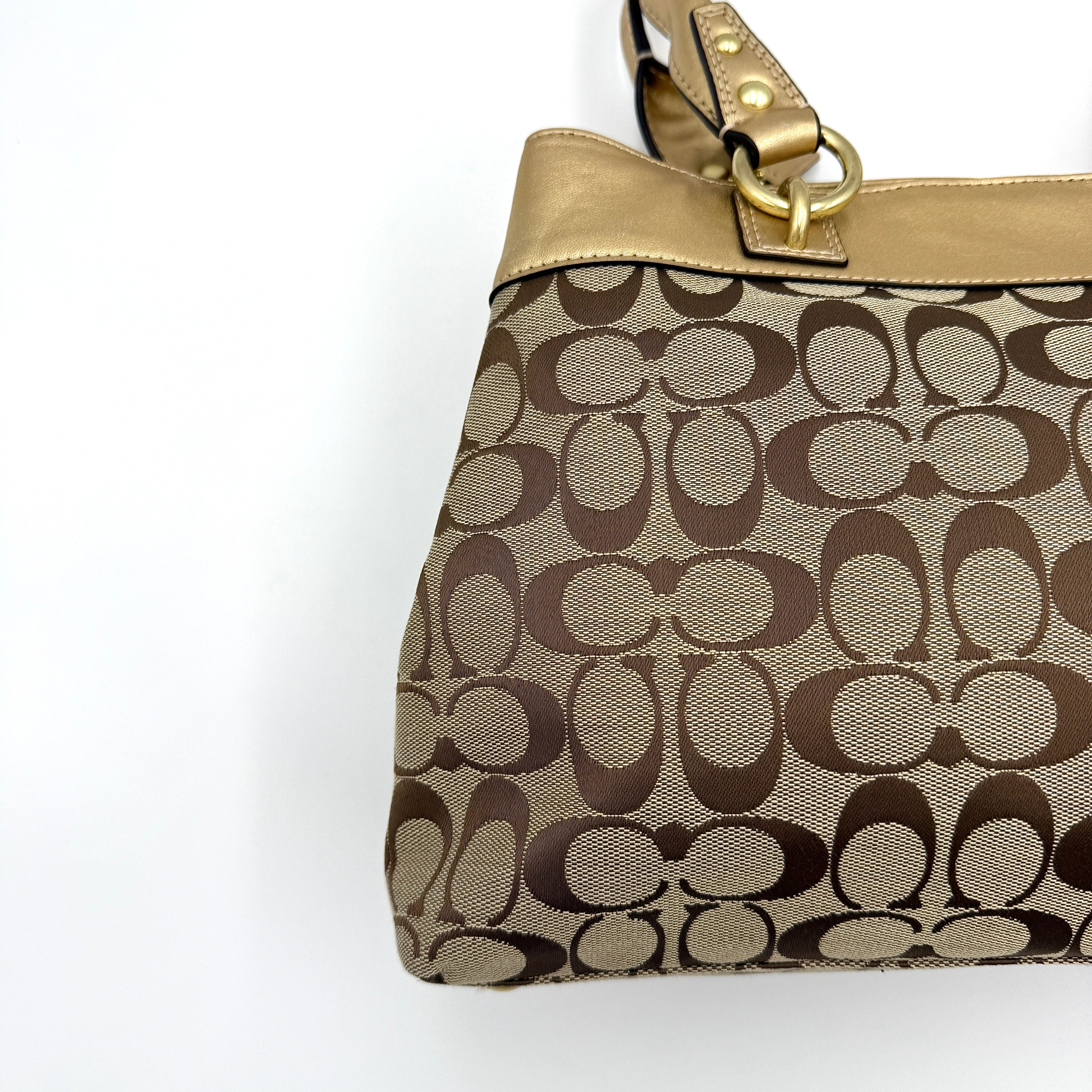 Coach Signature Penelope Shoulder Bag in beige monogram canvas with gold leather trim and gold-tone hardware displayed upright.