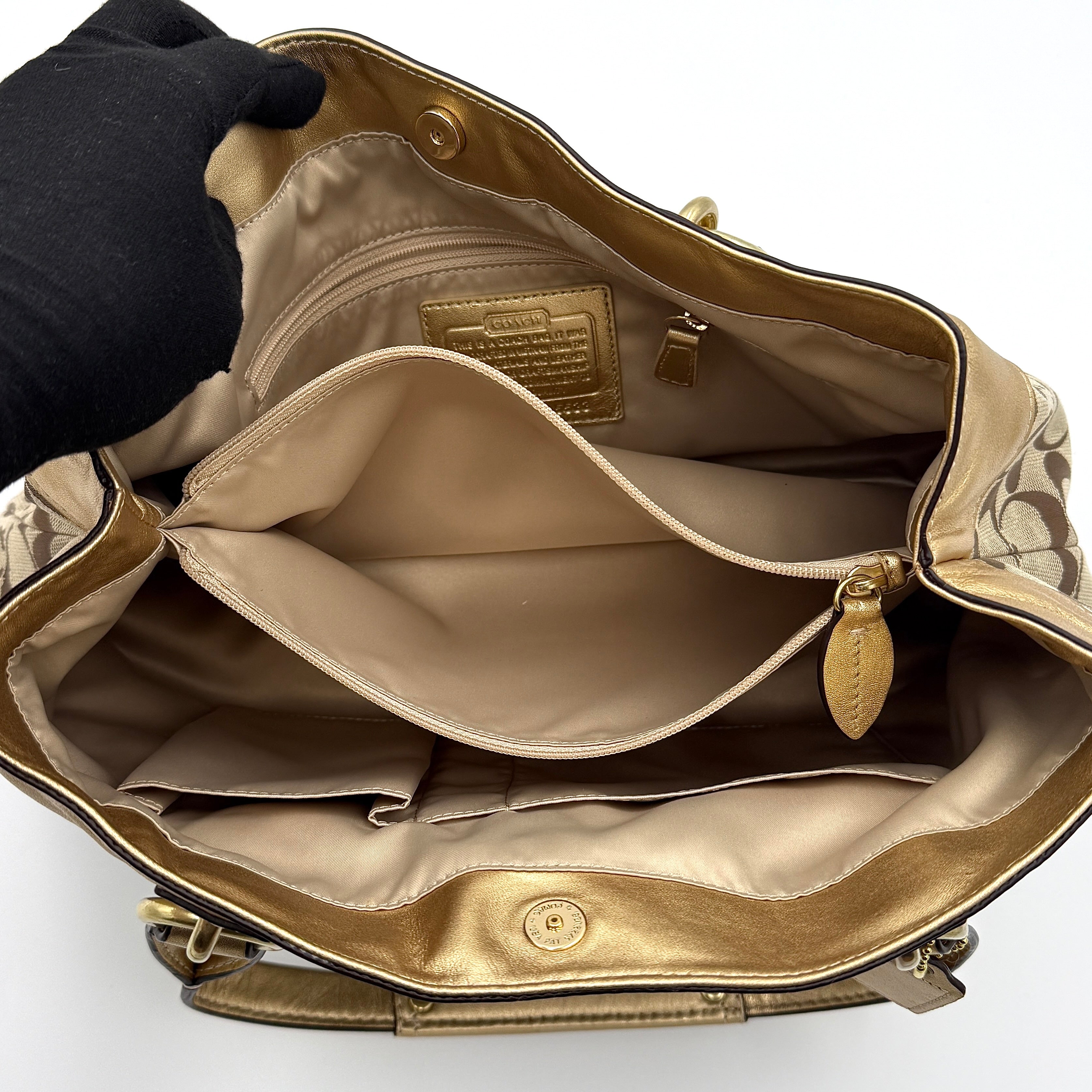 Coach Signature Penelope Shoulder Bag in beige monogram canvas with gold leather trim and gold-tone hardware displayed upright.