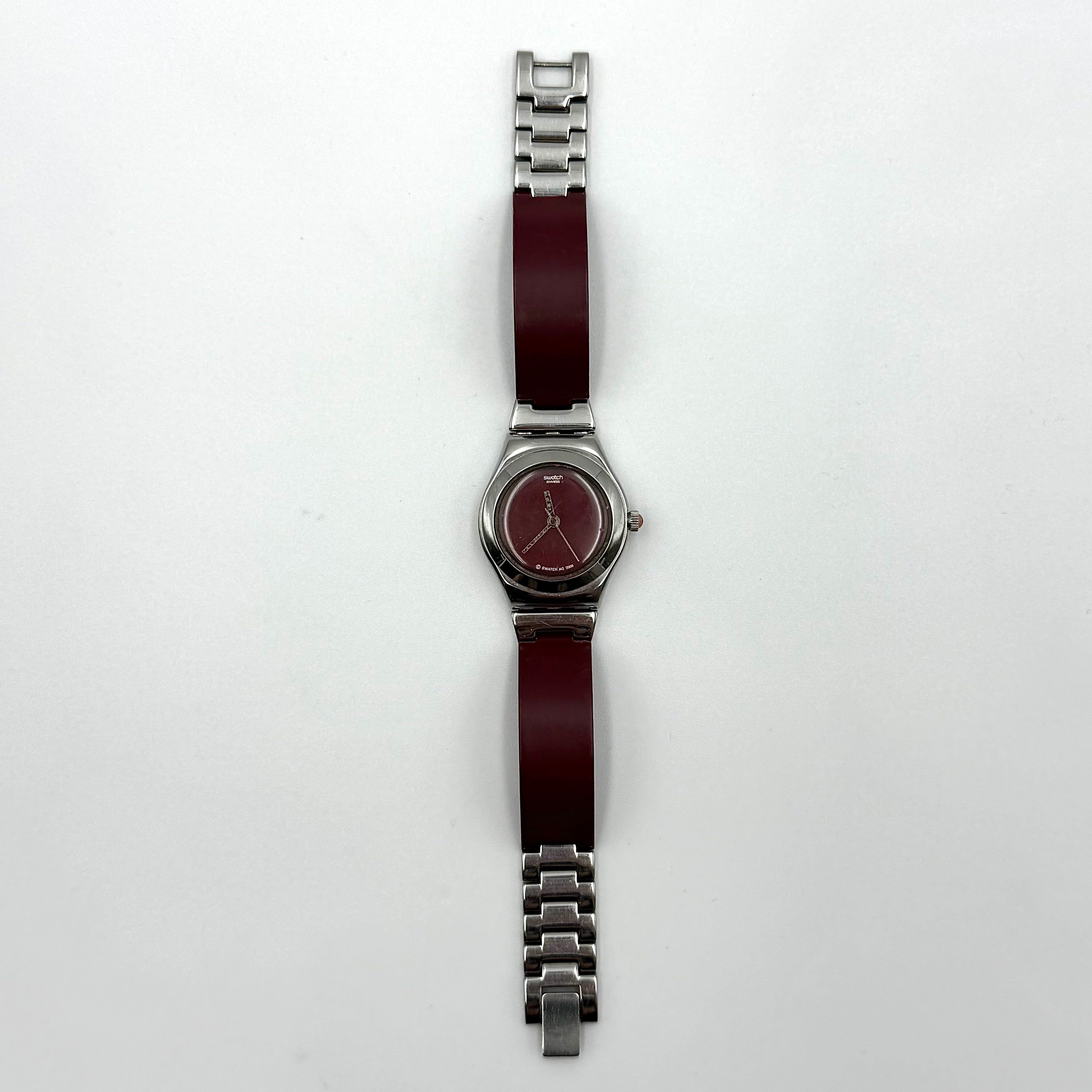 Swatch Irony Lady Angels Call watch in burgundy and silver, presented on a black cushion.