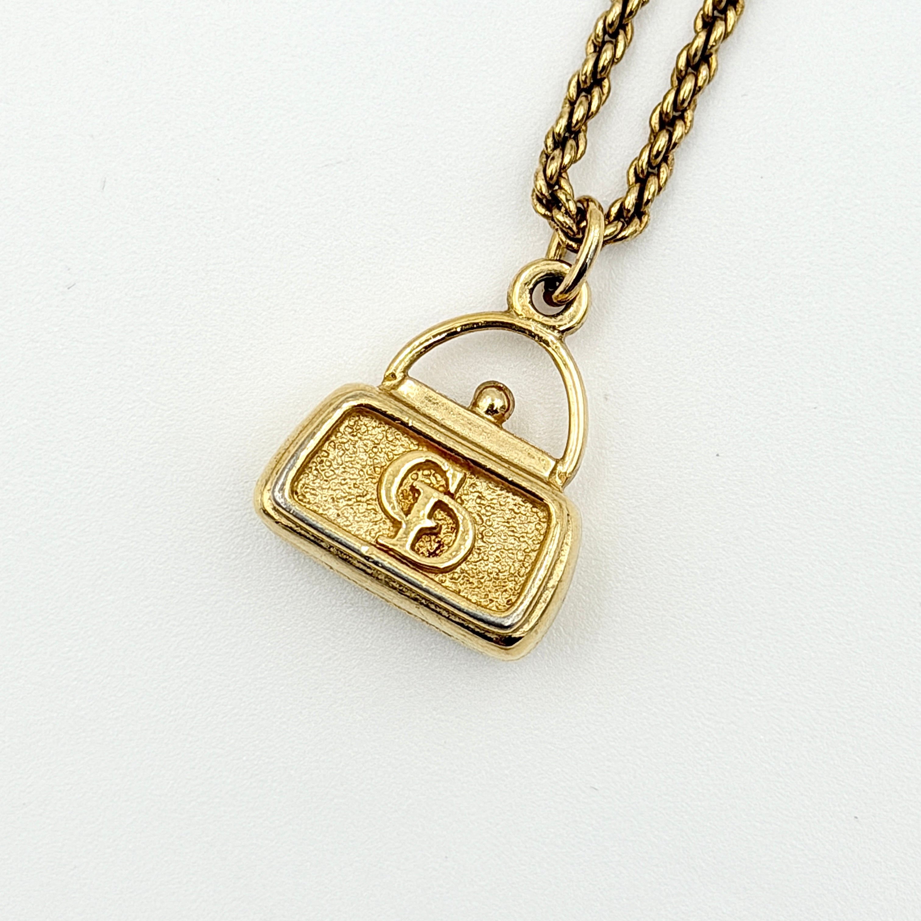 Dior gold necklace with a CD logo handbag pendant on a twisted chain, shown laid flat against a white background.