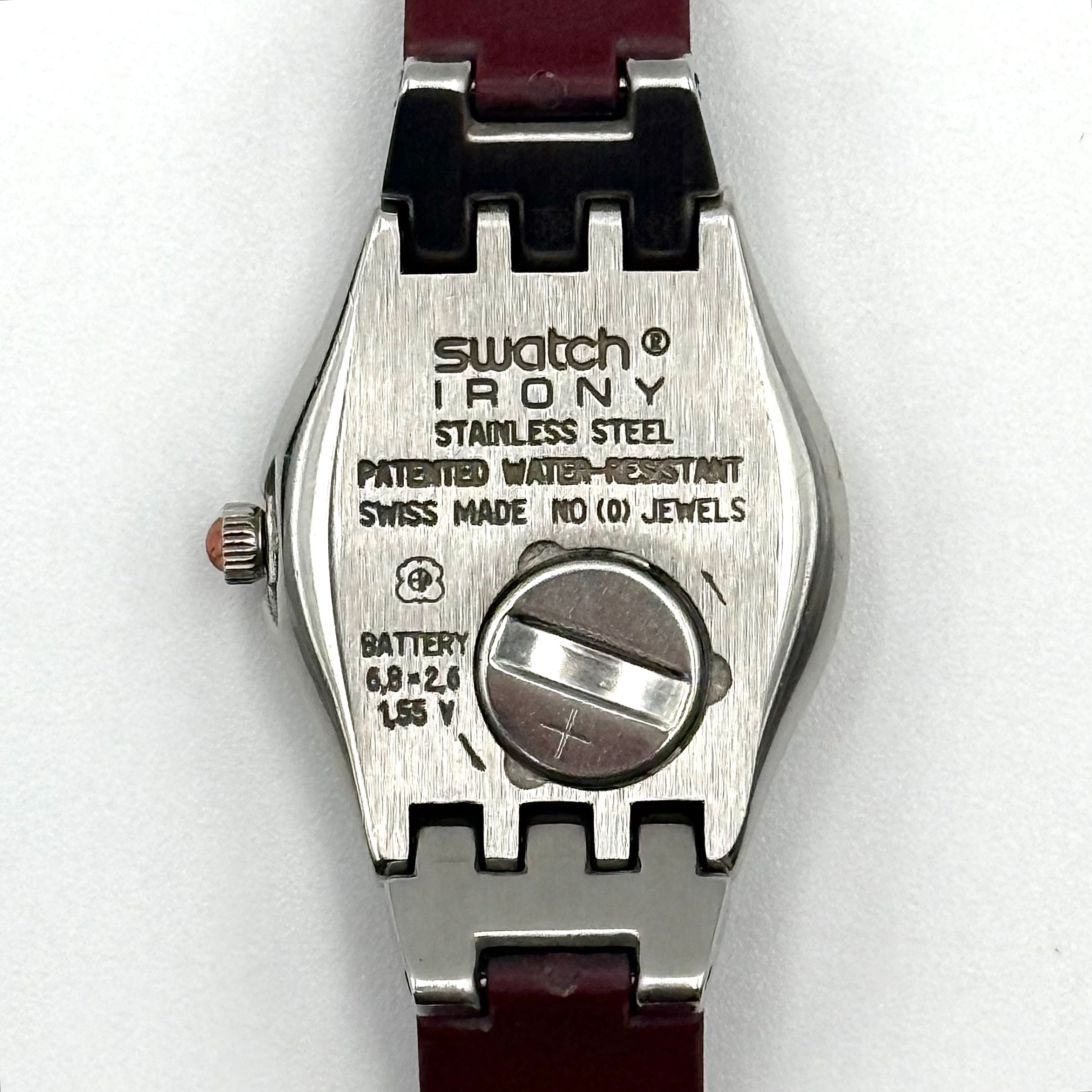 Swatch Irony Lady Angels Call watch in burgundy and silver, presented on a black cushion.