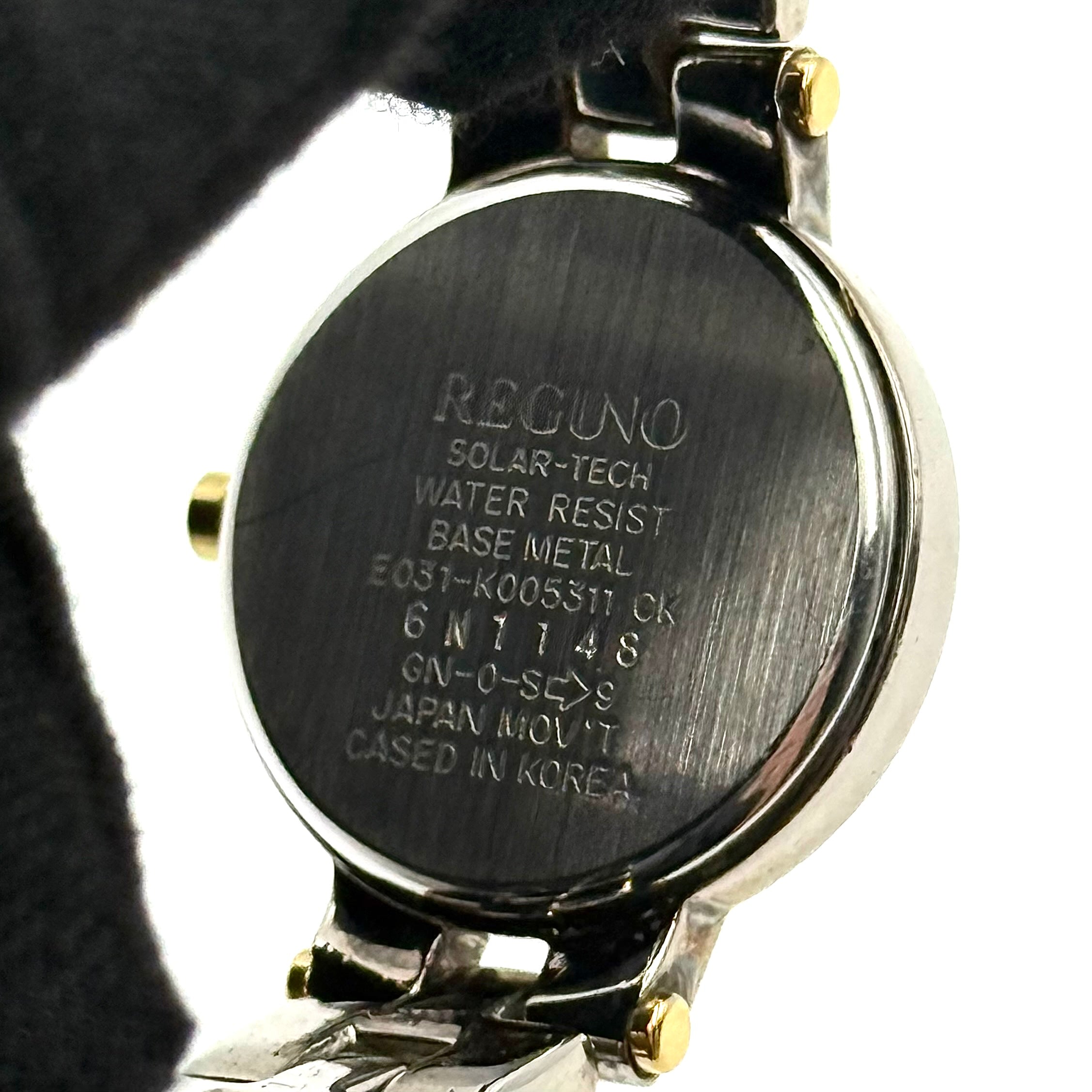 Citizen Reguno two-tone stainless steel watch in gold and silver with a round dial and linked bracelet, displayed on a black pillow.