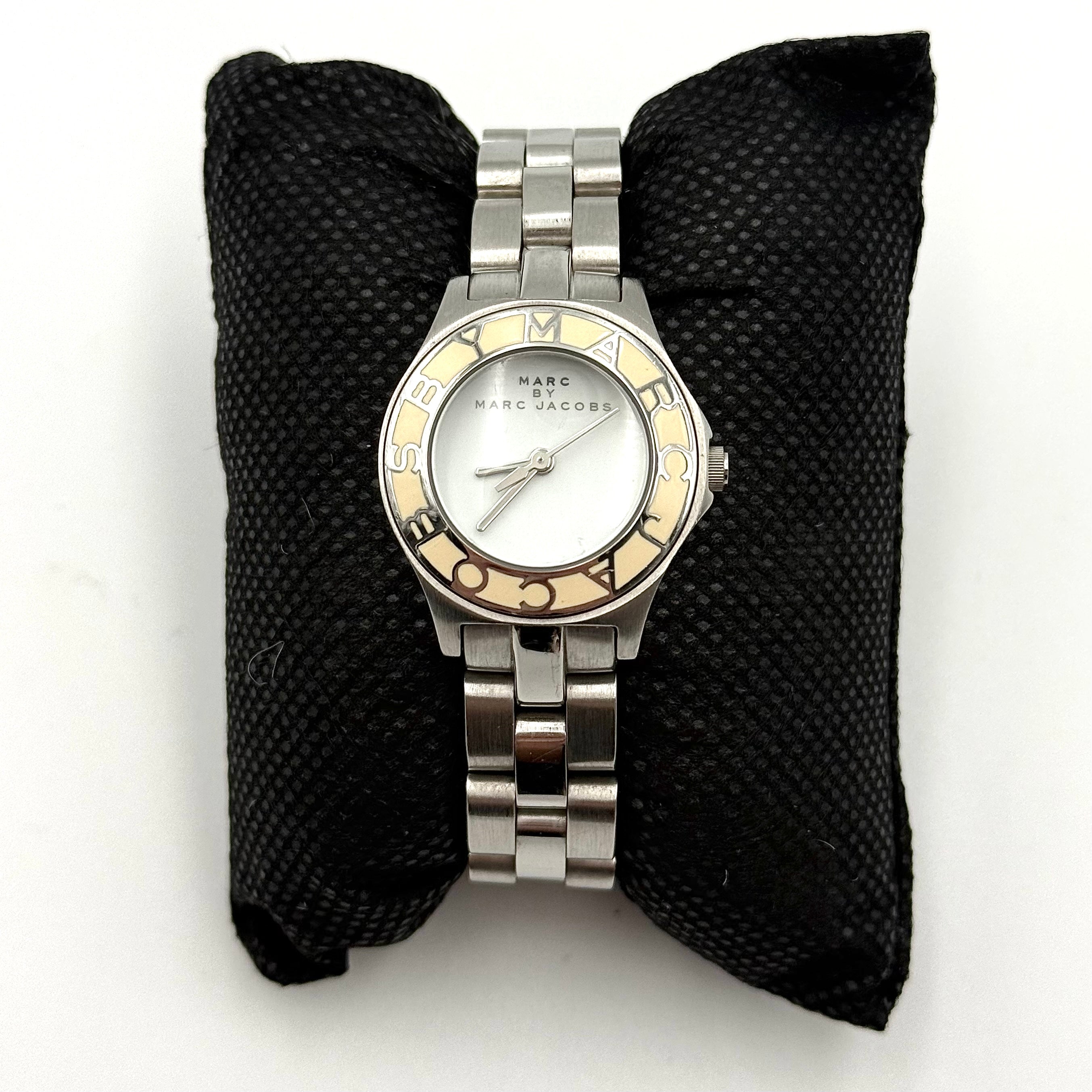 Marc Jacobs Blade MBM3049 watch in stainless steel with a cream bezel, shown on a black cushion.