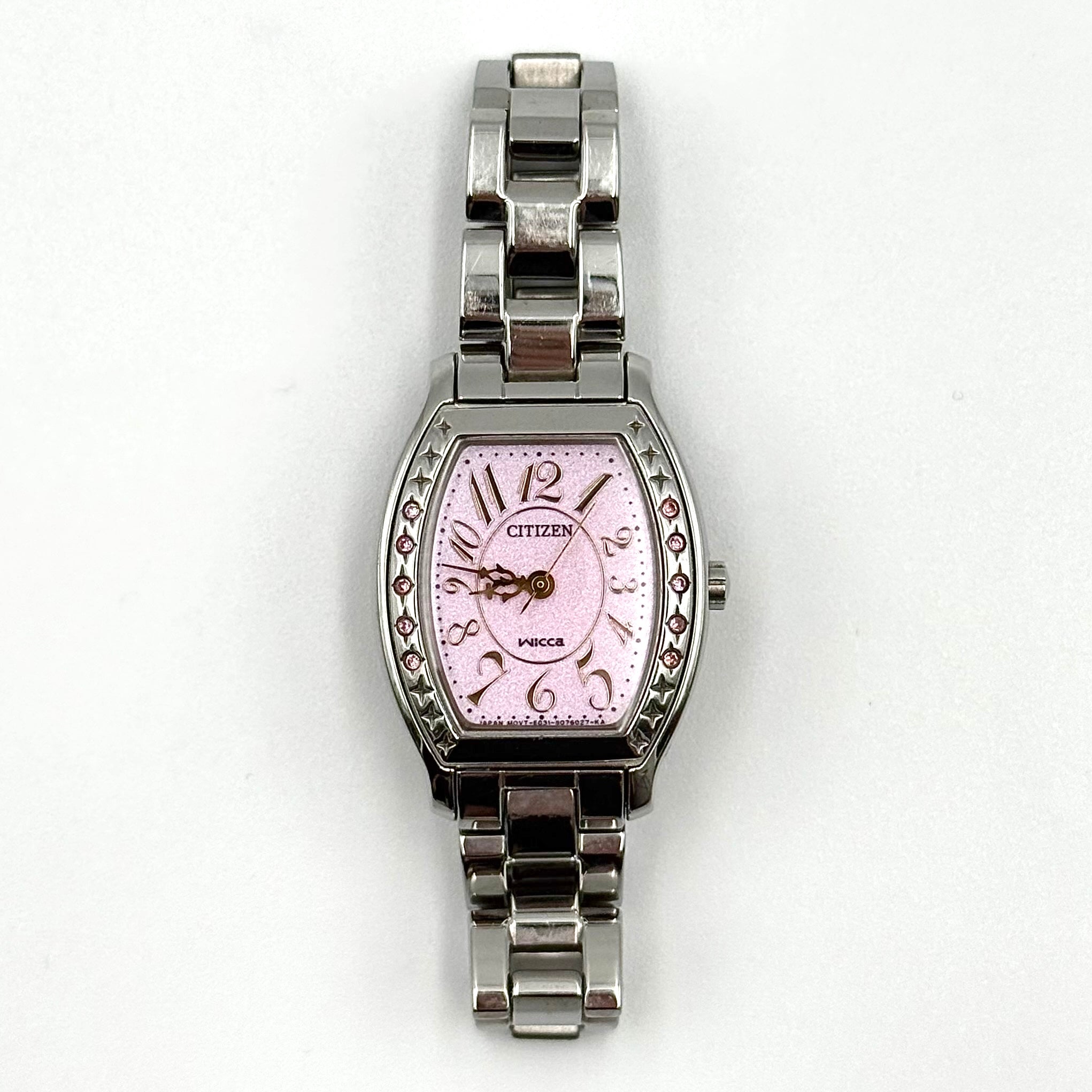 Citizen Wicca stainless steel watch with pink dial and star-detailed bezel shown on a black cushion.