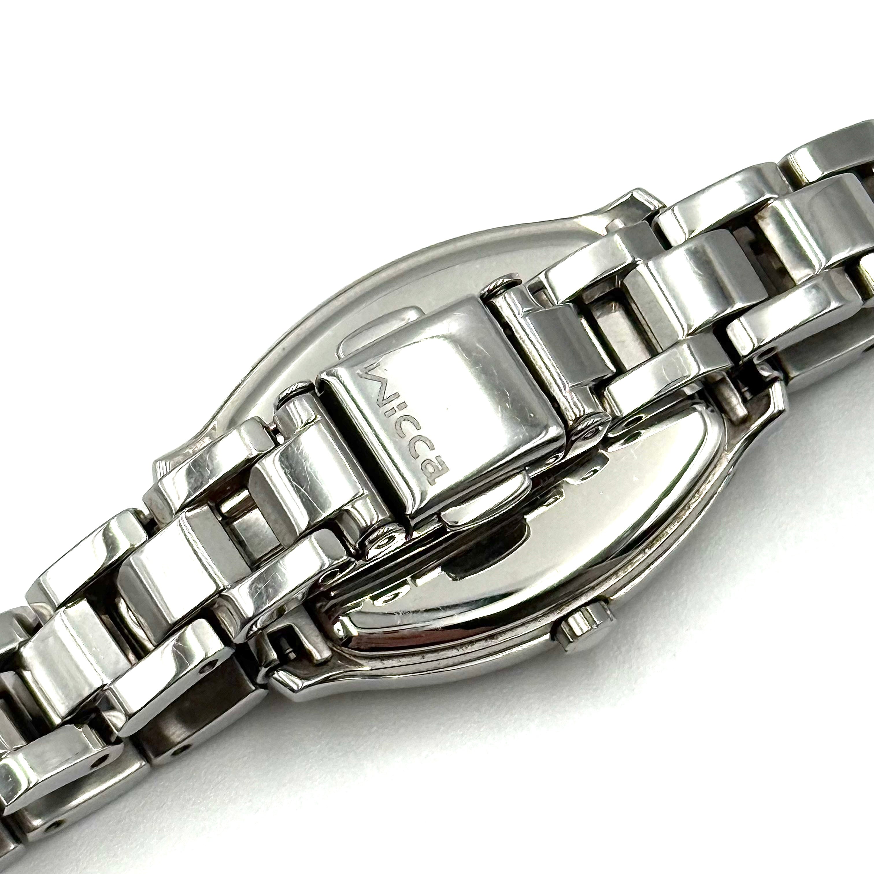 Citizen Wicca stainless steel watch with pink dial and star-detailed bezel shown on a black cushion.