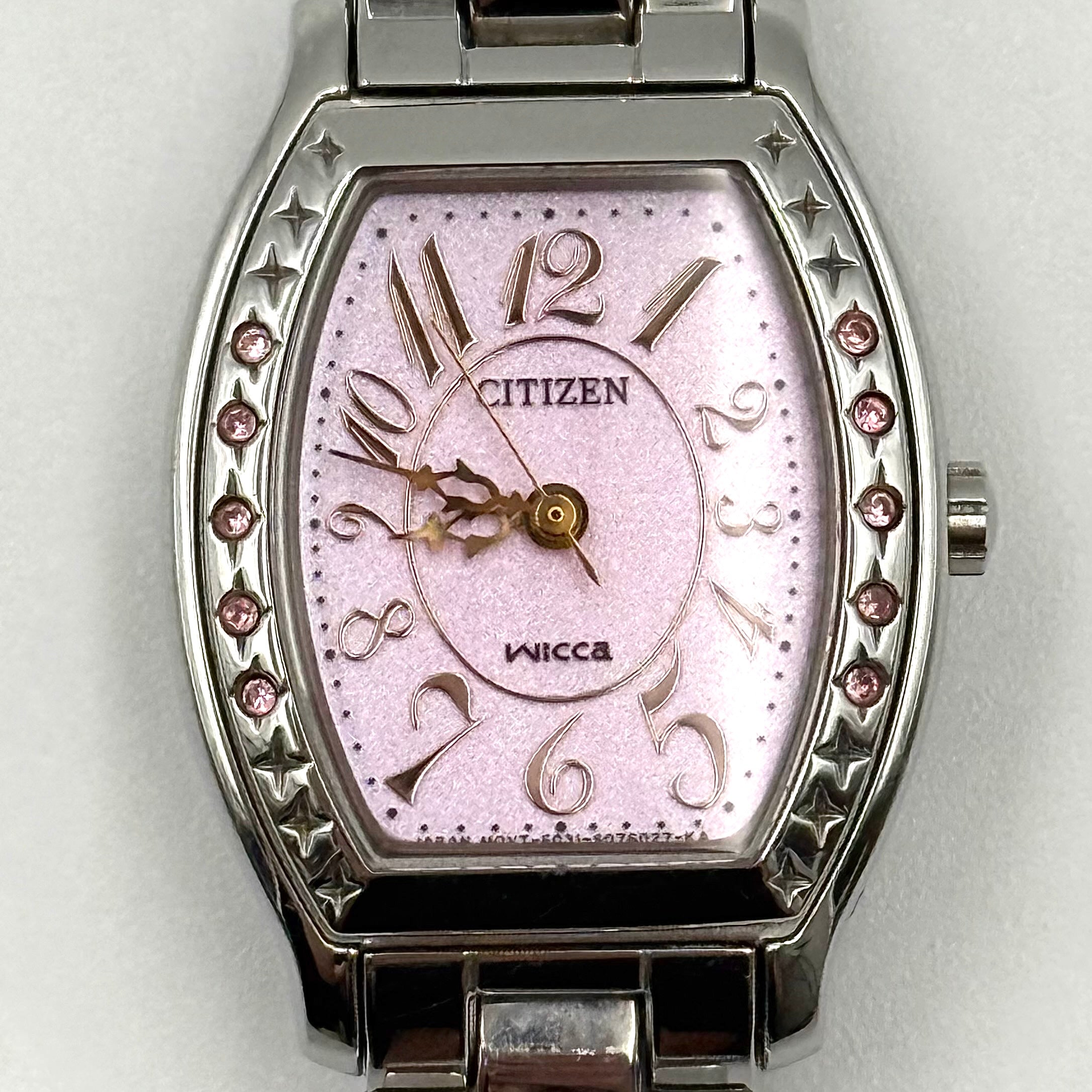 Citizen Wicca stainless steel watch with pink dial and star-detailed bezel shown on a black cushion.