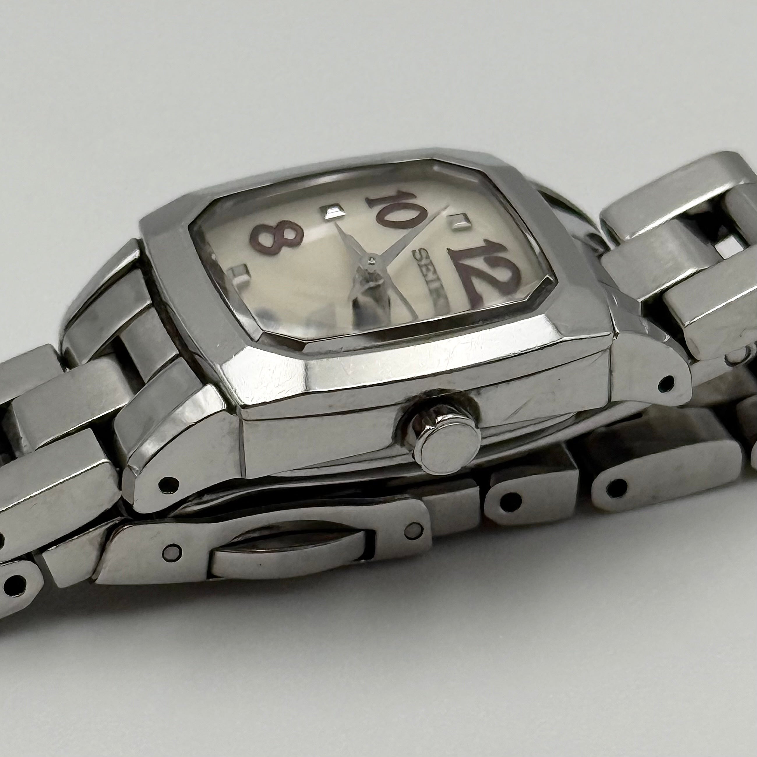 Seiko Lukia stainless steel watch with a rectangular case and silver dial presented on a cushion.