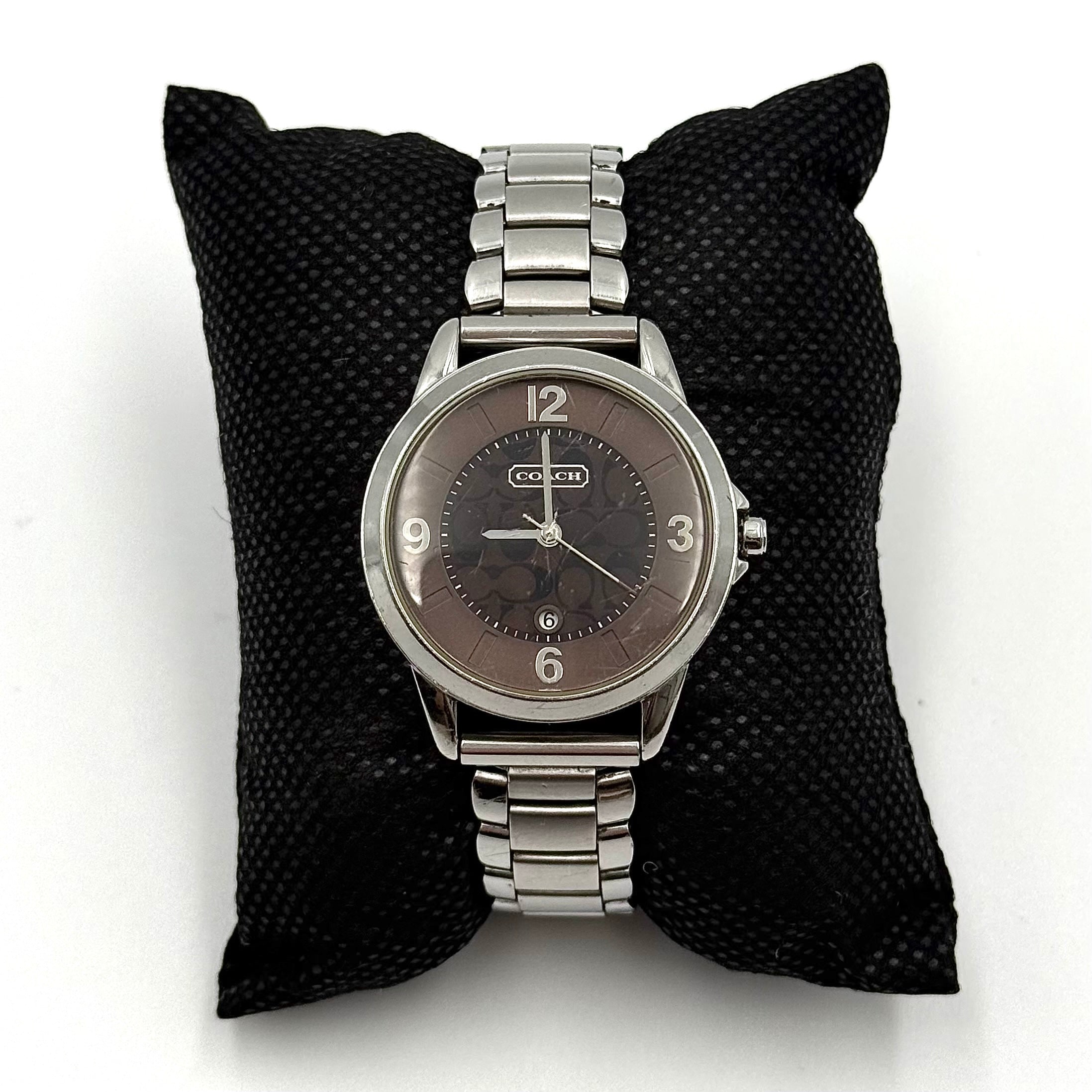 Coach CA.13.7.14.0431 stainless steel watch with brown dial and silver-tone bracelet, presented on a black cushion.