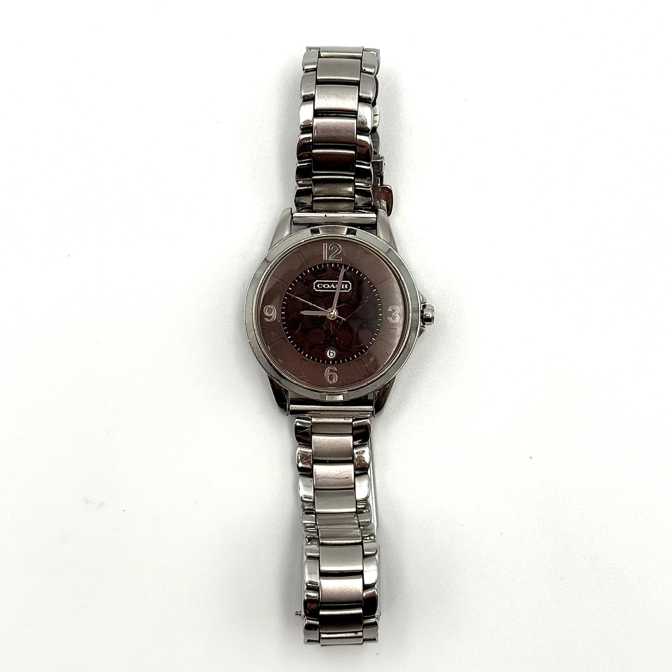 Coach CA.13.7.14.0431 stainless steel watch with brown dial and silver-tone bracelet, presented on a black cushion.