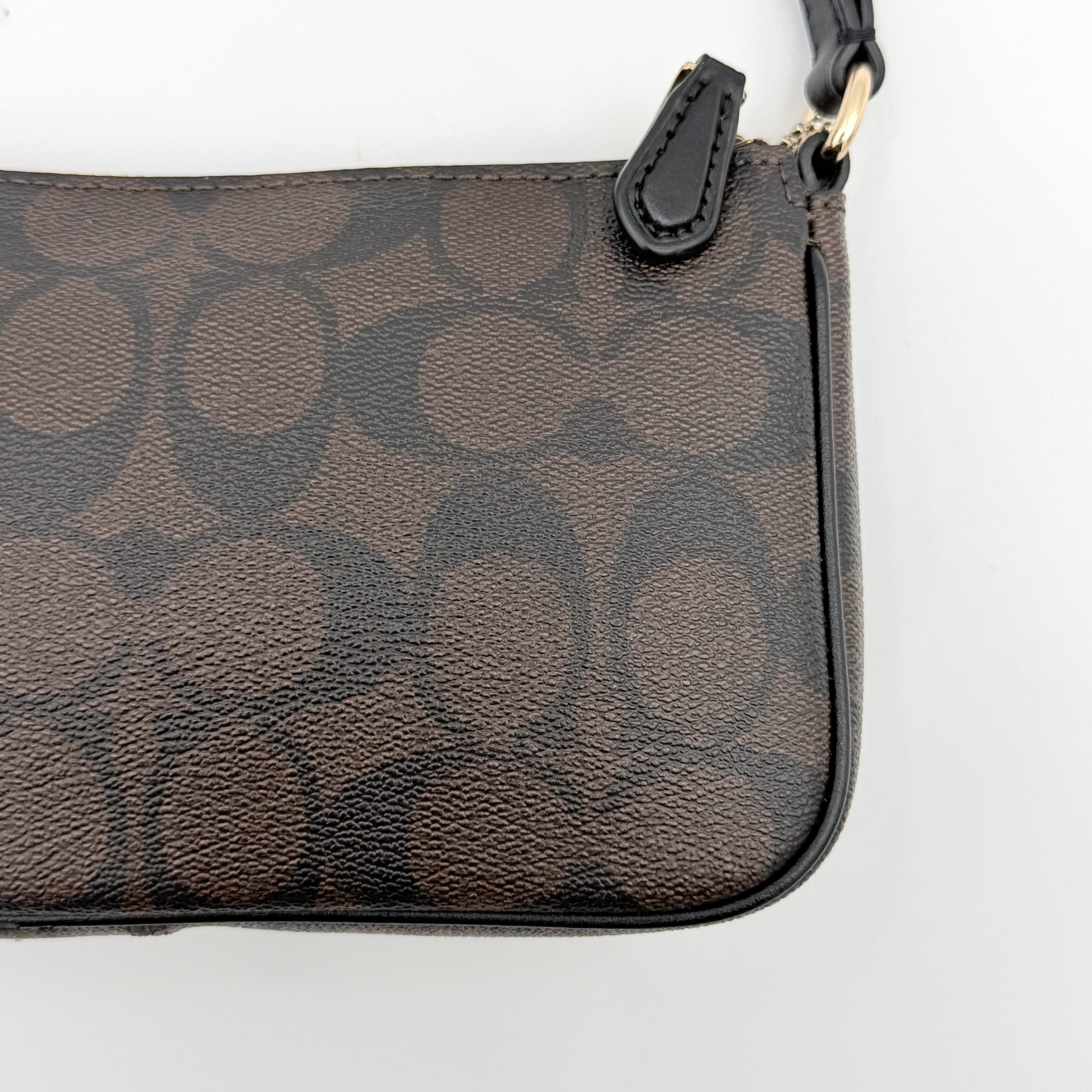Coach Signature Nolita 19 shoulder bag in brown monogram canvas with black leather strap and gold-tone hardware, shown against a white background.