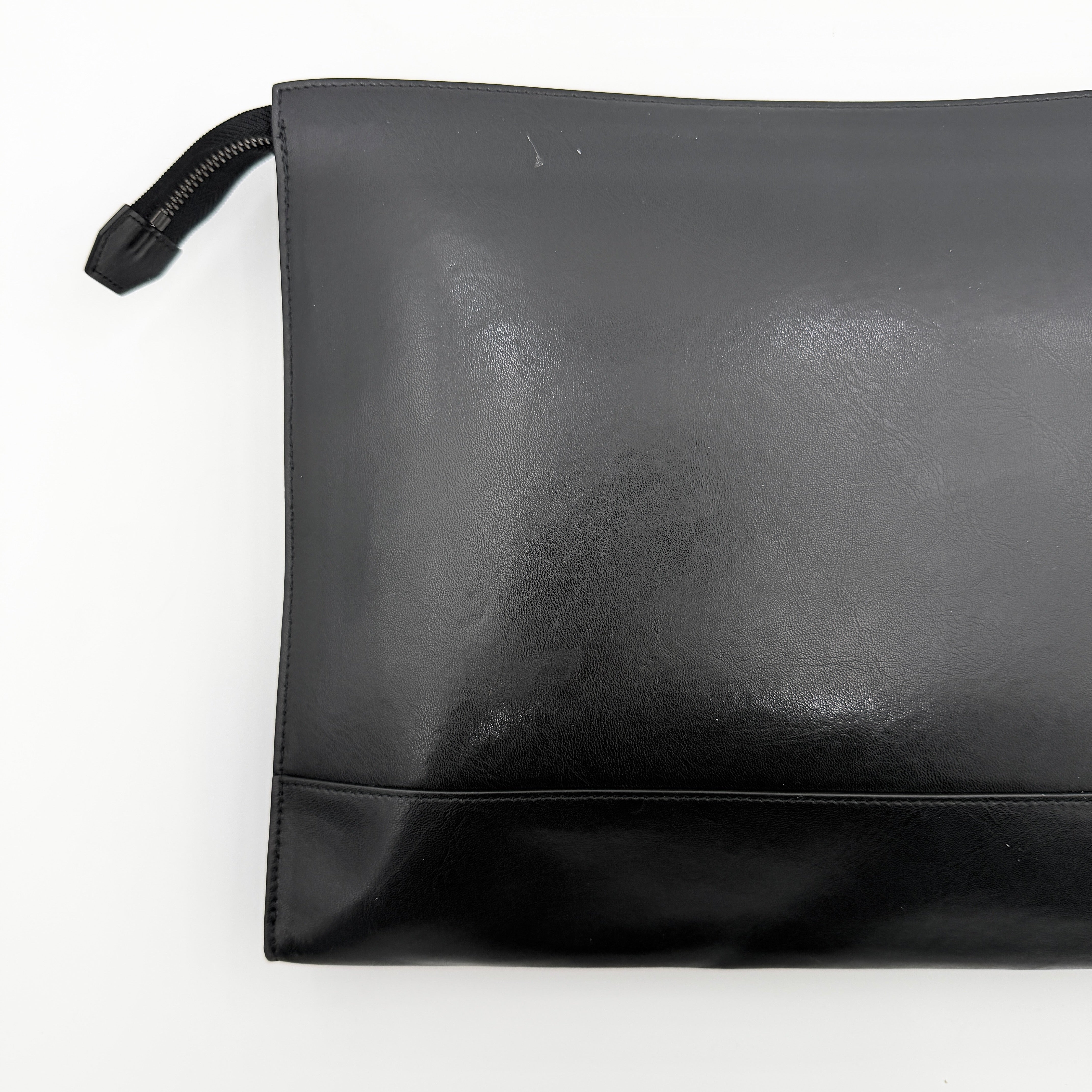 Front view of a Givenchy black leather clutch with bold white logo panel and red zip pull.
